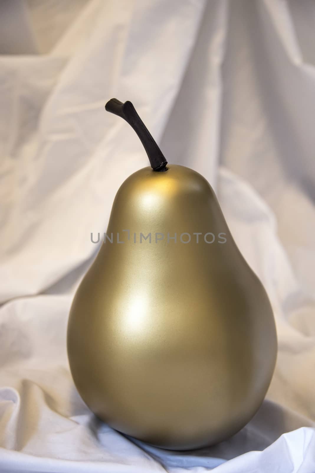 UK, October 2017: 	Gold / Golden Pear on crumpled white fabric background