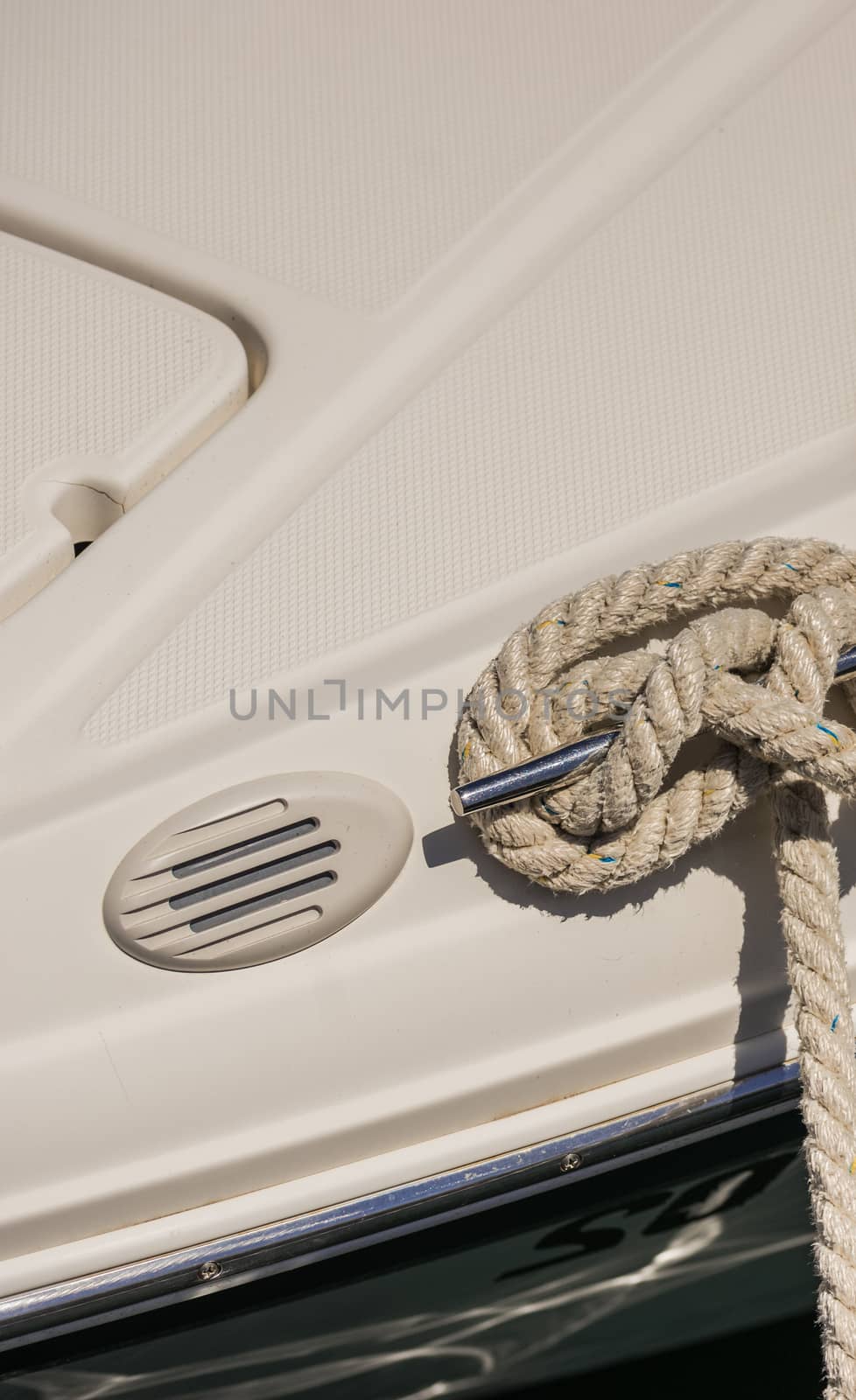 Close-up of nautical mooring rope is knotted on boat cleat
