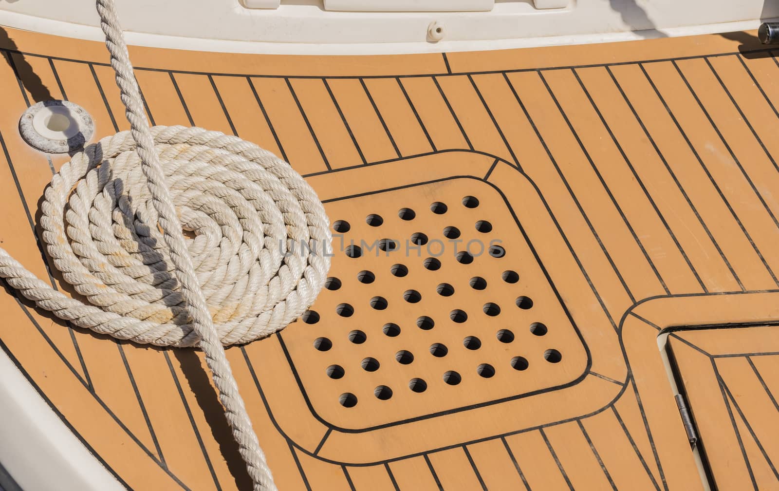 Close-up of curled mooring rope on boat deck at marina harbor
