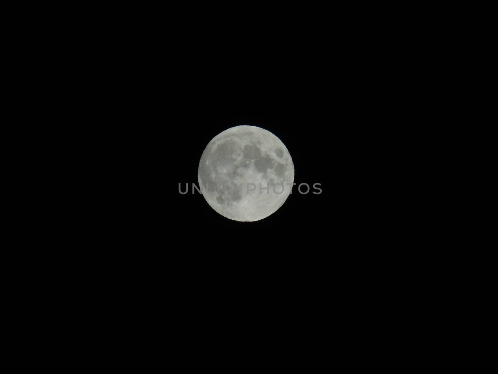 Genova, Italy - 07/05/2020: An amazing photography of the full moon over the city of Genova by night with a great clear and blue sky in the background and some stars.