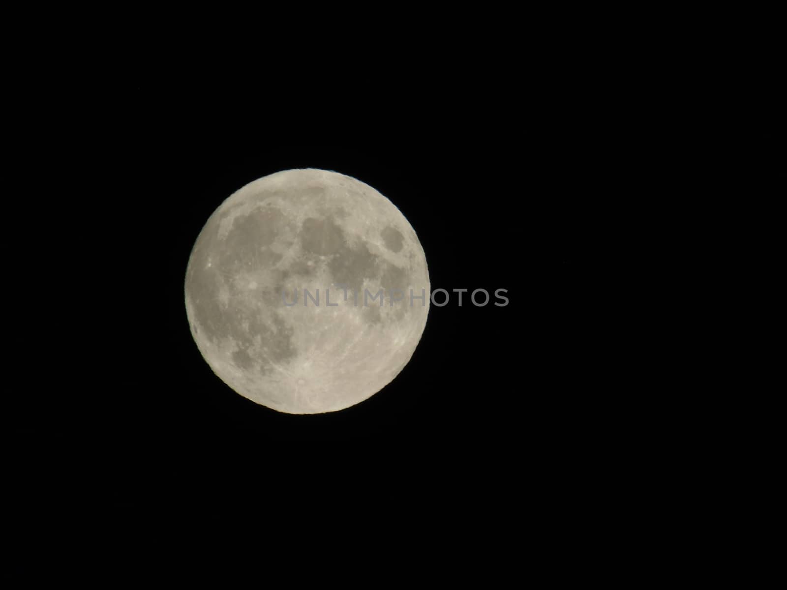 Genova, Italy - 07/05/2020: An amazing photography of the full moon over the city of Genova by night with a great clear and blue sky in the background and some stars.