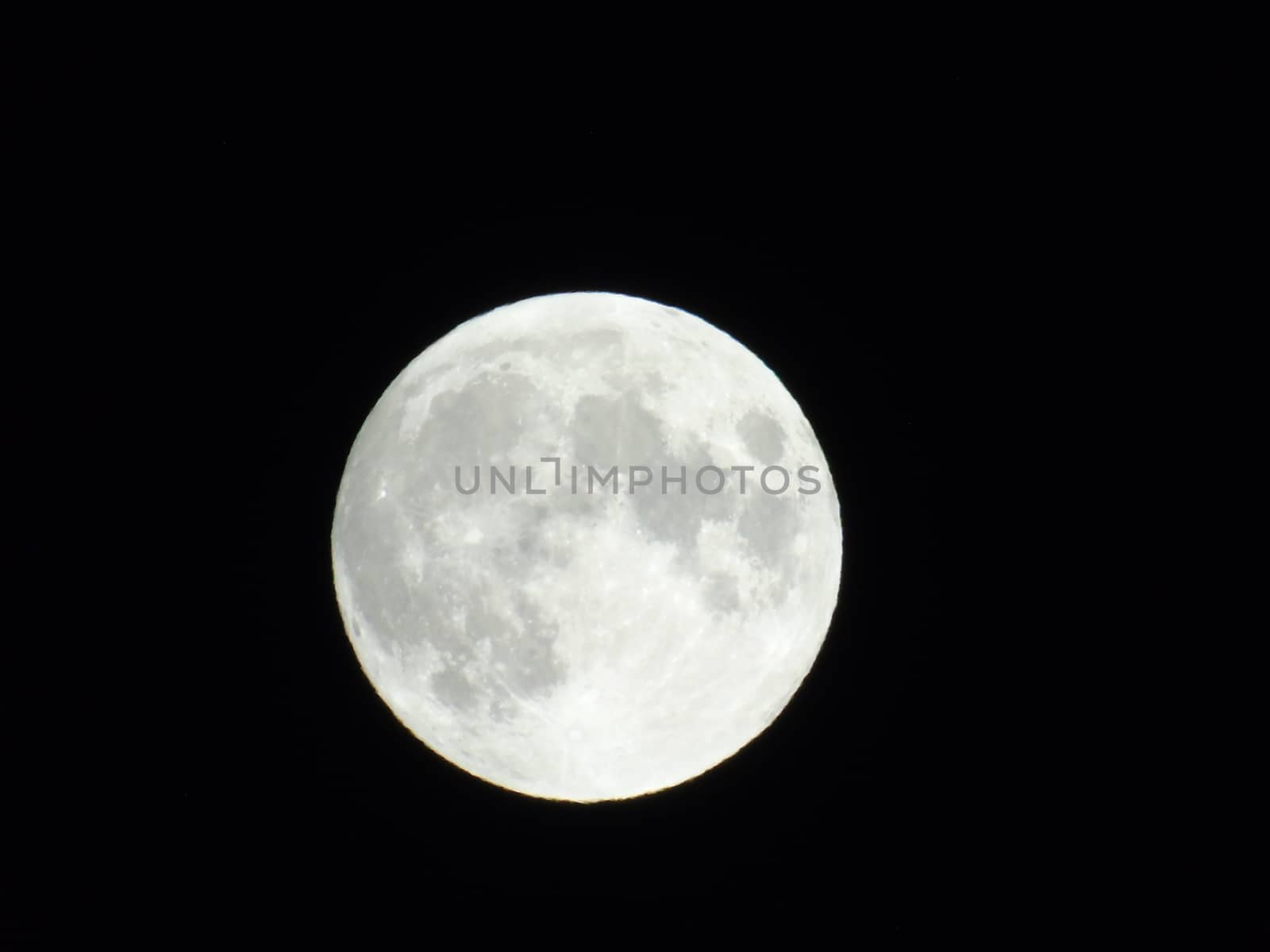 Genova, Italy - 07/05/2020: An amazing photography of the full moon over the city of Genova by night with a great clear and blue sky in the background and some stars.