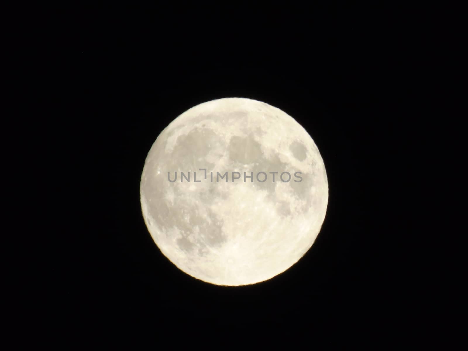 Genova, Italy - 07/05/2020: An amazing photography of the full moon over the city of Genova by night with a great clear and blue sky in the background and some stars.