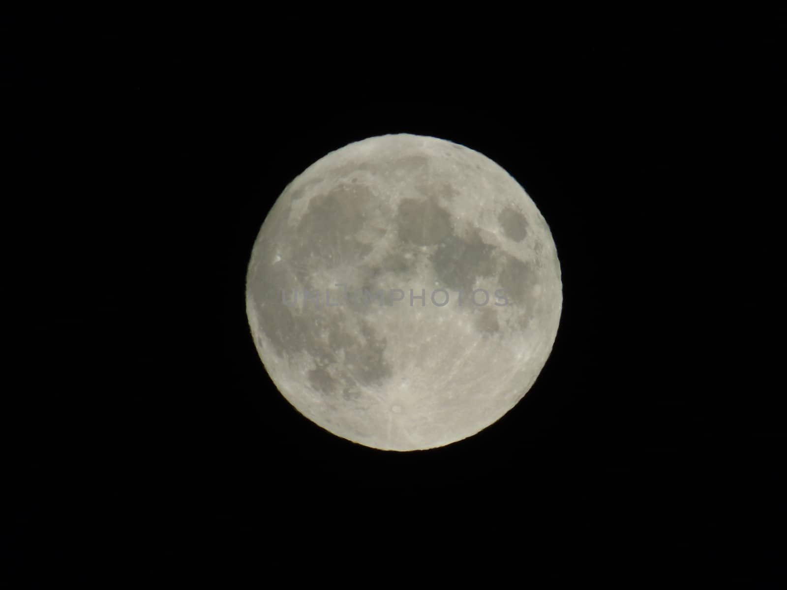 Genova, Italy - 07/05/2020: An amazing photography of the full moon over the city of Genova by night with a great clear and blue sky in the background and some stars.