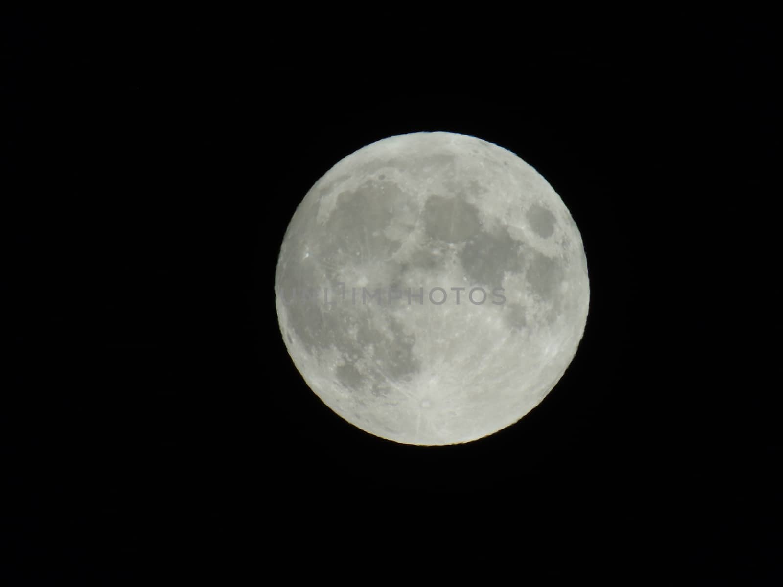 Genova, Italy - 07/05/2020: An amazing photography of the full moon over the city of Genova by night with a great clear and blue sky in the background and some stars.