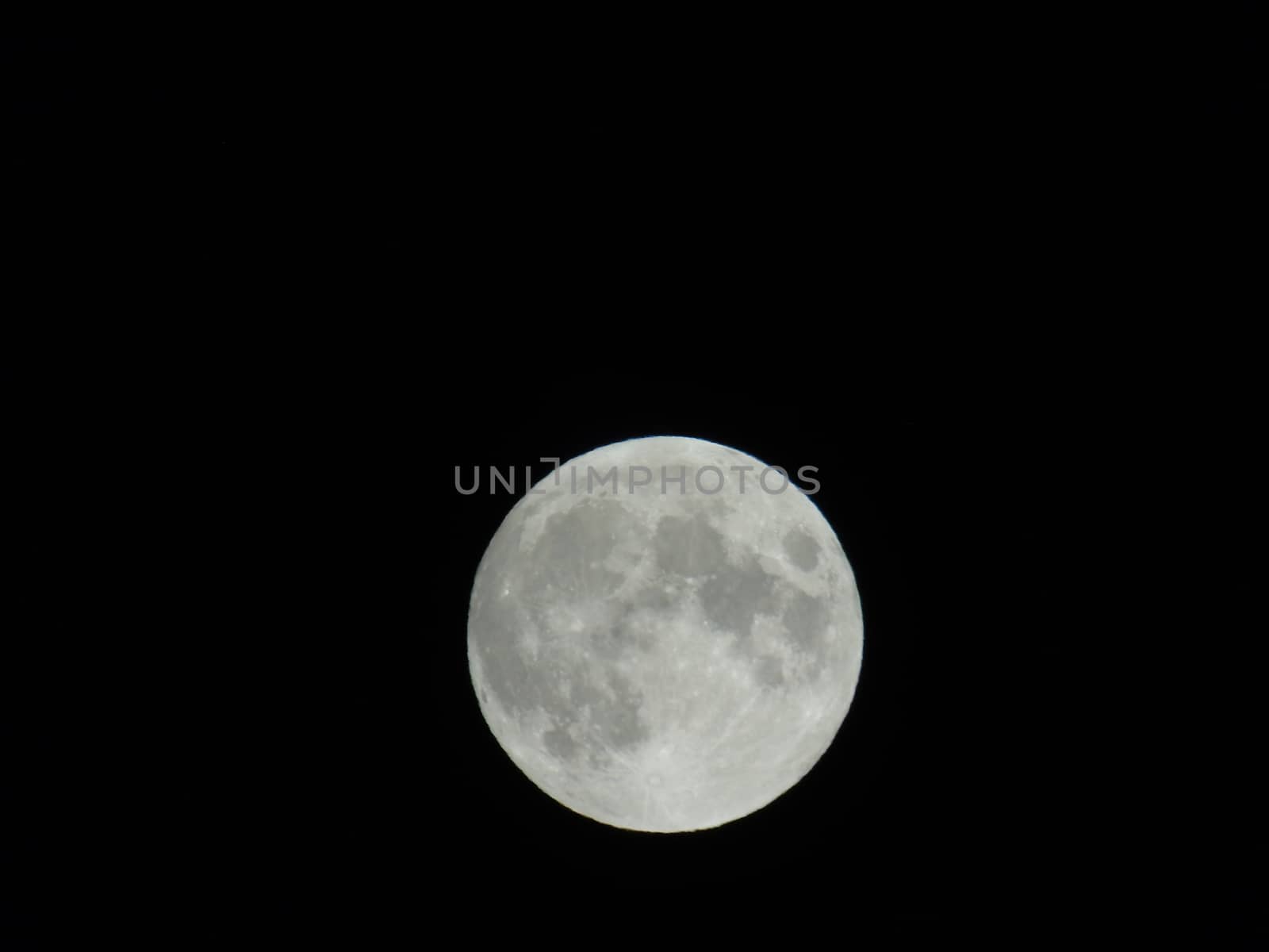 Genova, Italy - 07/05/2020: An amazing photography of the full moon over the city of Genova by night with a great clear and blue sky in the background and some stars.