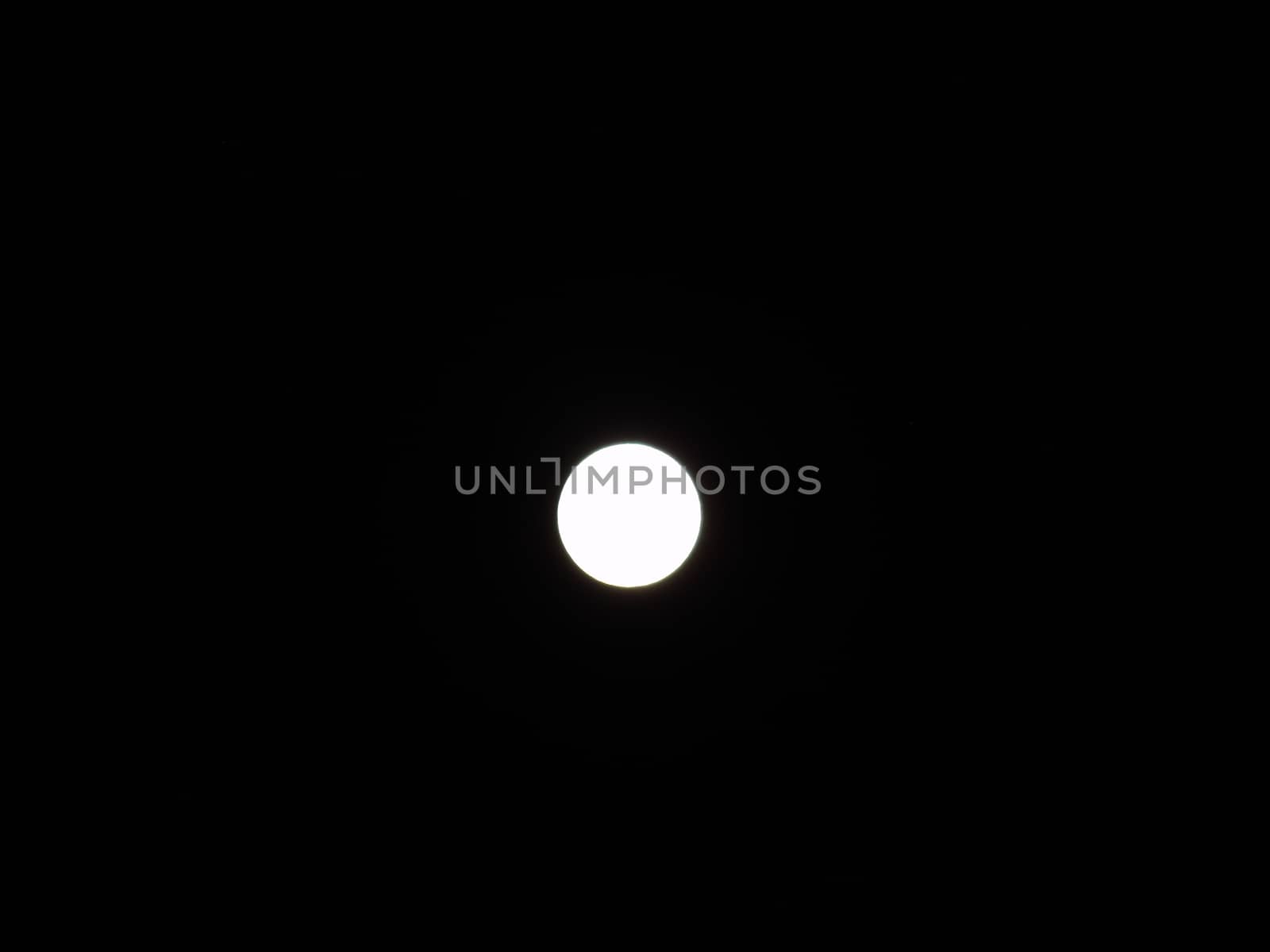 Genova, Italy - 07/05/2020: An amazing photography of the full moon over the city of Genova by night with a great clear and blue sky in the background and some stars.