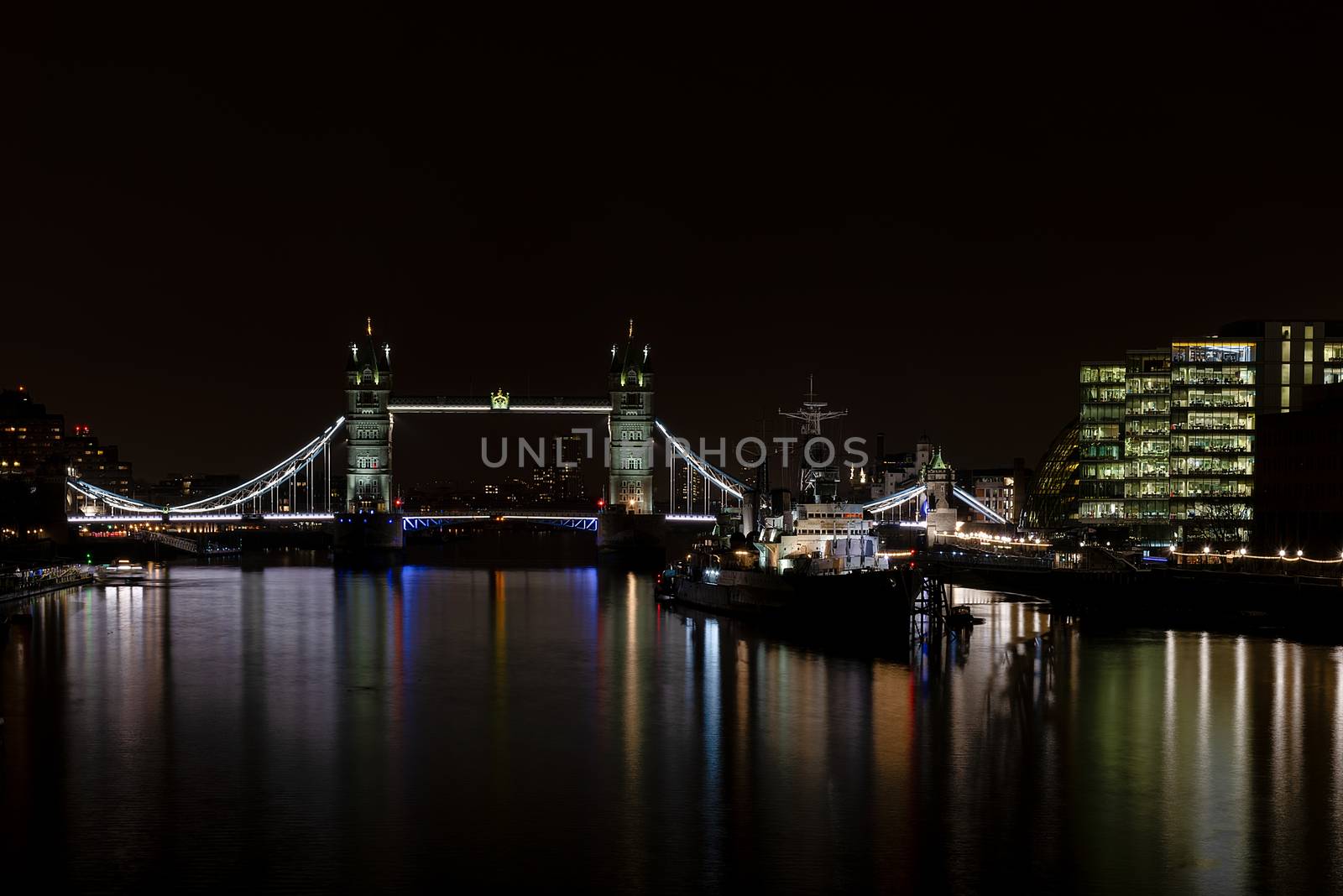 London, UK - Jan 2020:  Night time cityscape featuring HMS Belfast floating on the river Thames next to Tower Bridge. Long exposure.