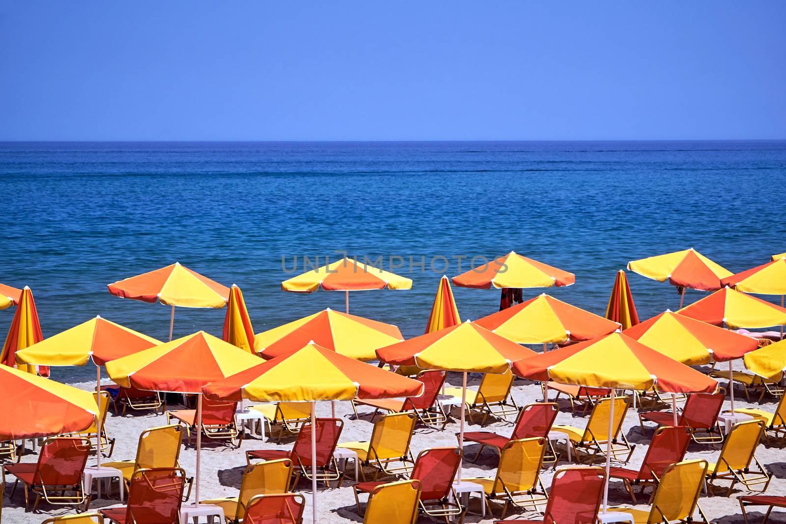 Umbrellas and beds on a sandy beach on the island of Crete