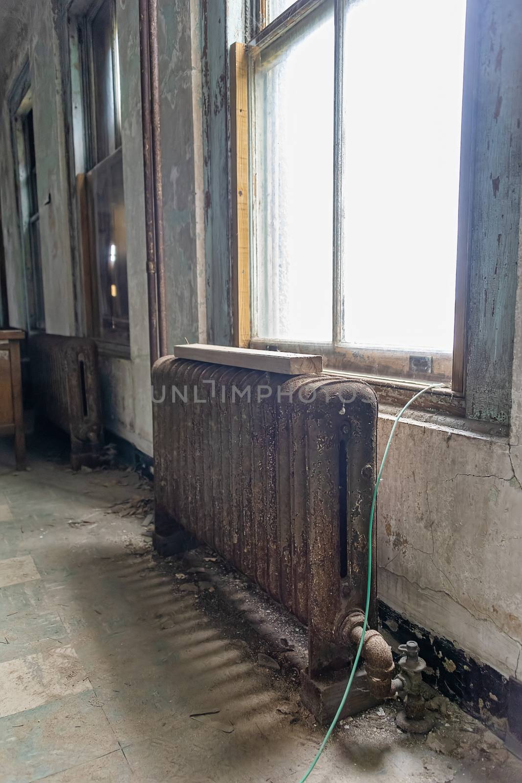 USA, New York, Ellis Island - May 2019: vintage cast iron radiator rusting inside an abandoned hospital ward  