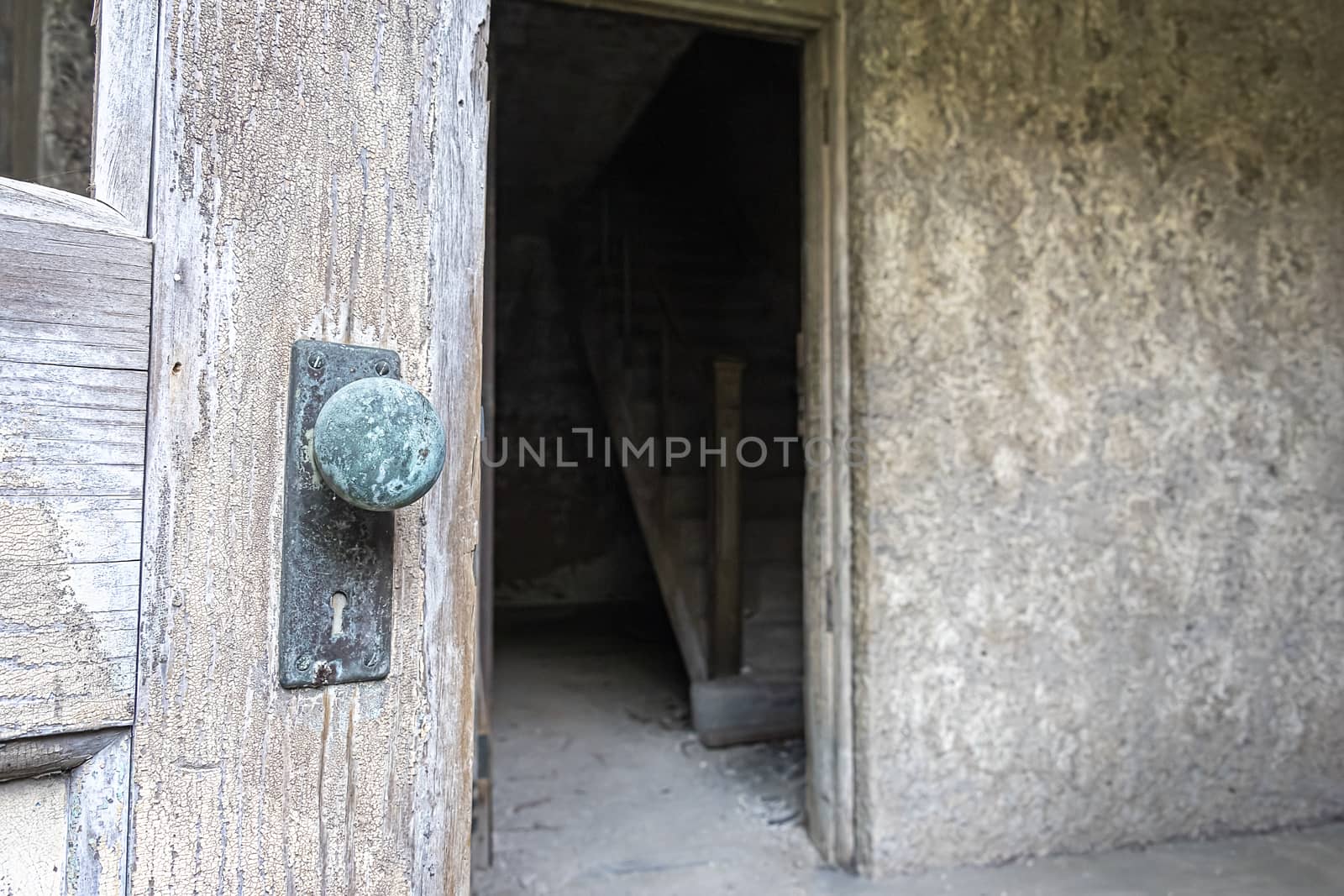 USA, New York, Ellis Island - May 2019: Close up of corroded green door handle and the entrance to a dark stairway in an abandoned building
