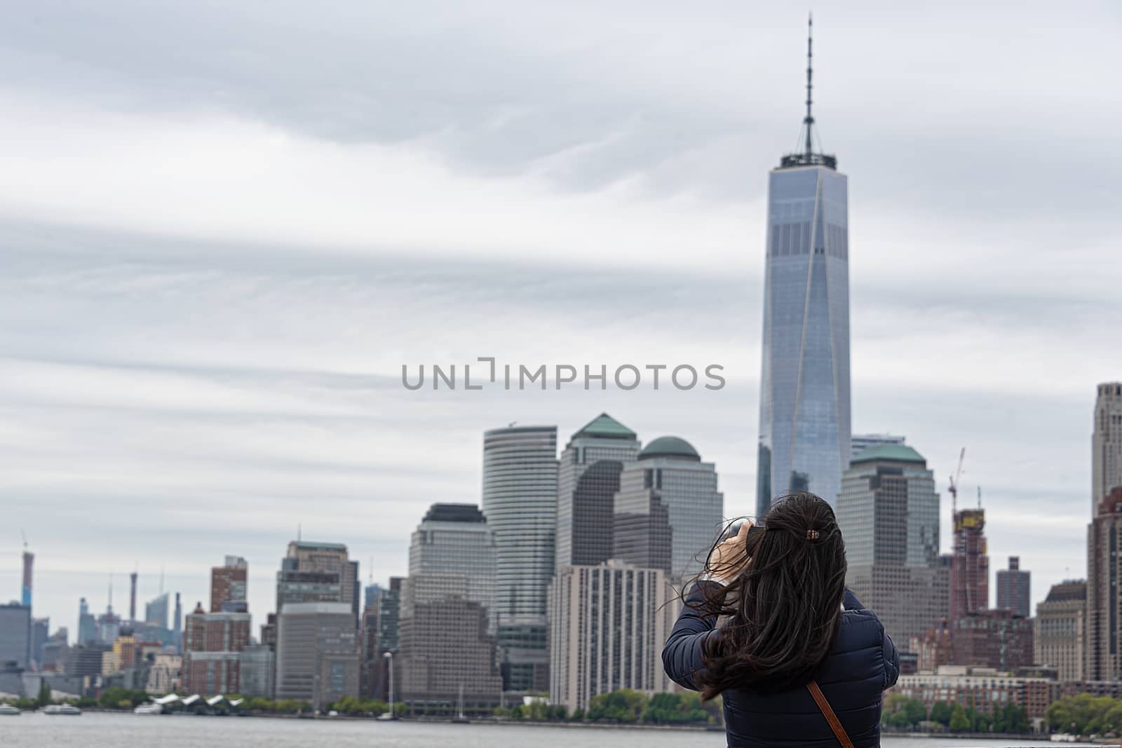 USA, New York, Ellis Island - May 2019: Unidentified woman photographing New York sky line