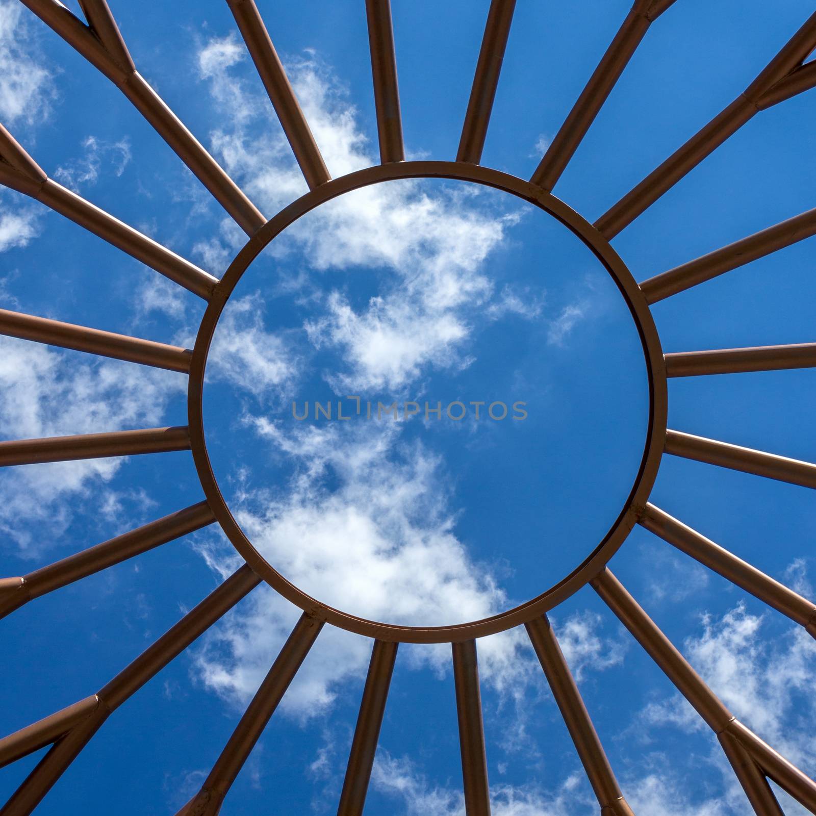 Steel structure with the shape of the sun and blue sky on the background.