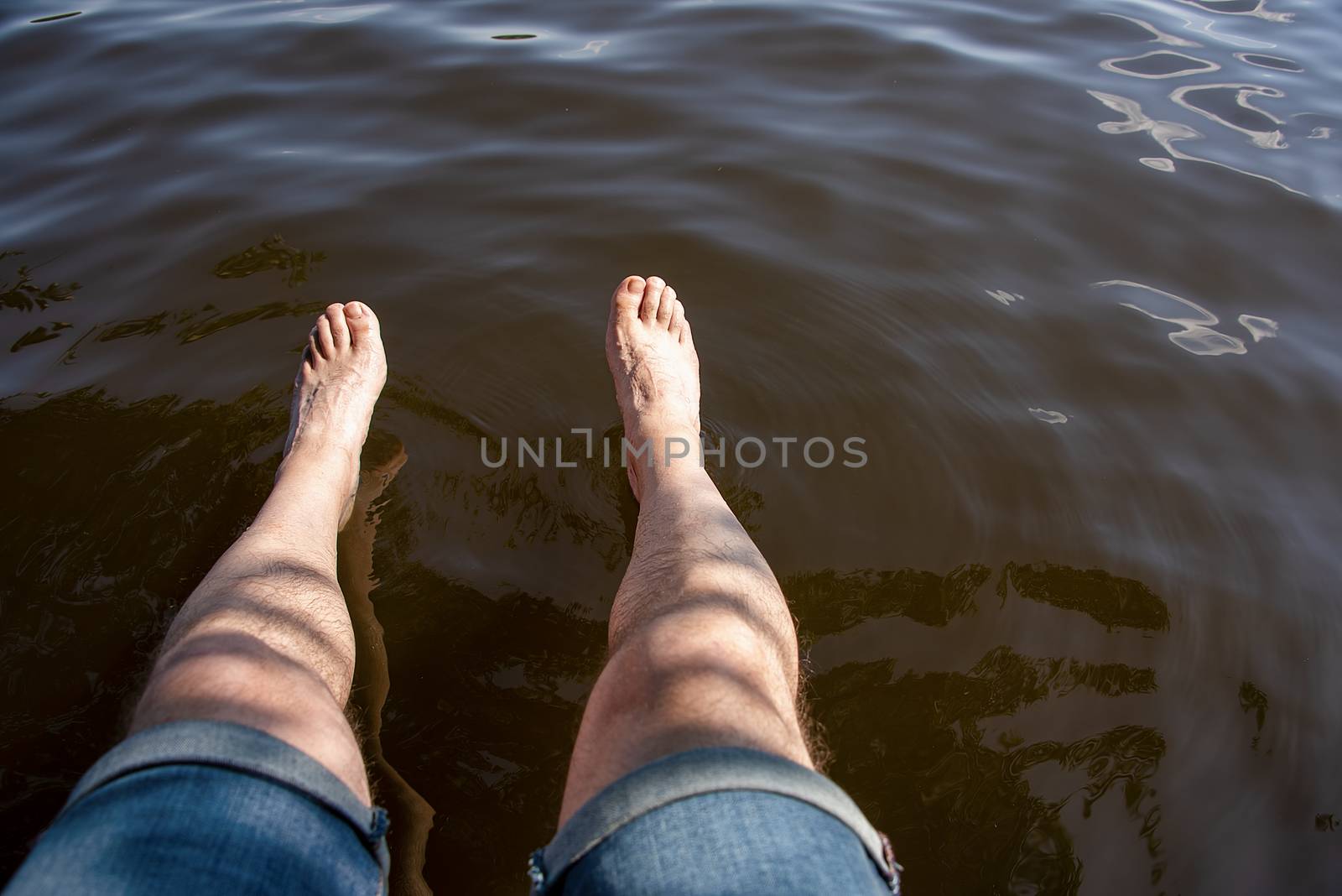 Romania - Aug 2019: Mans leg dangling in to water