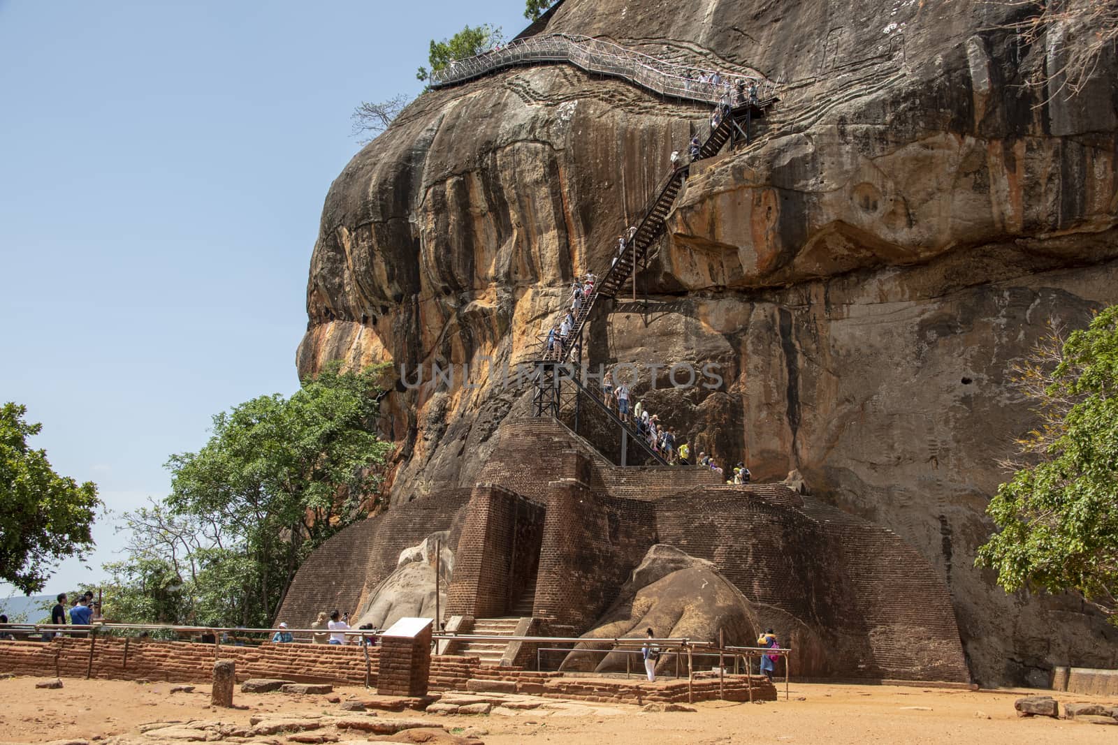 Sri lanka, Sept 2015: Tourists climb to the top of the rock above the ruins of the ancient lions feet at the palace entrance