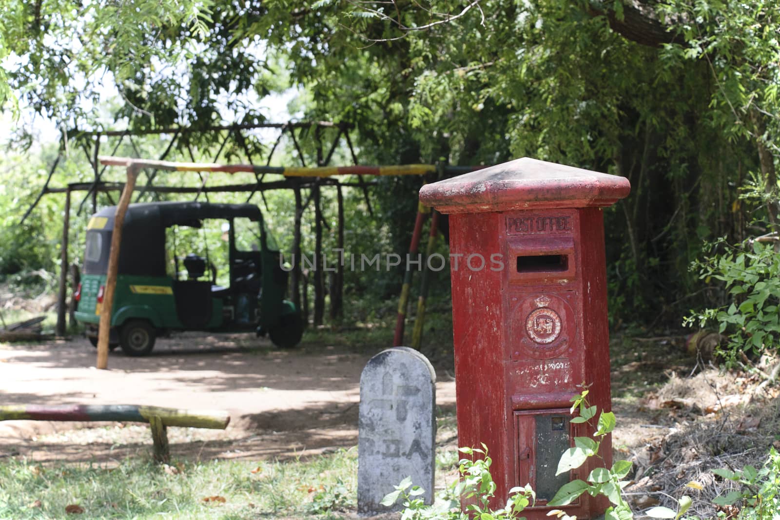 IGYRIYA, SRI LANAKA - August 25 2015: Mail box left over from the influence of colonial rule in Sri Lanka. Tuktuk parked in shaded background.