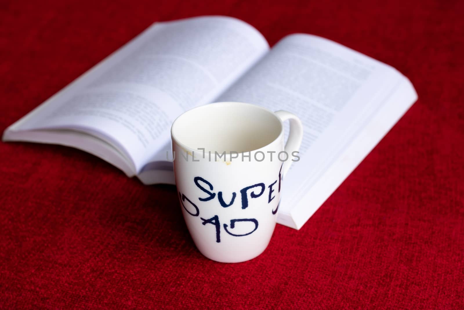 Stained coffee mug with an open book on a red sofa/couch