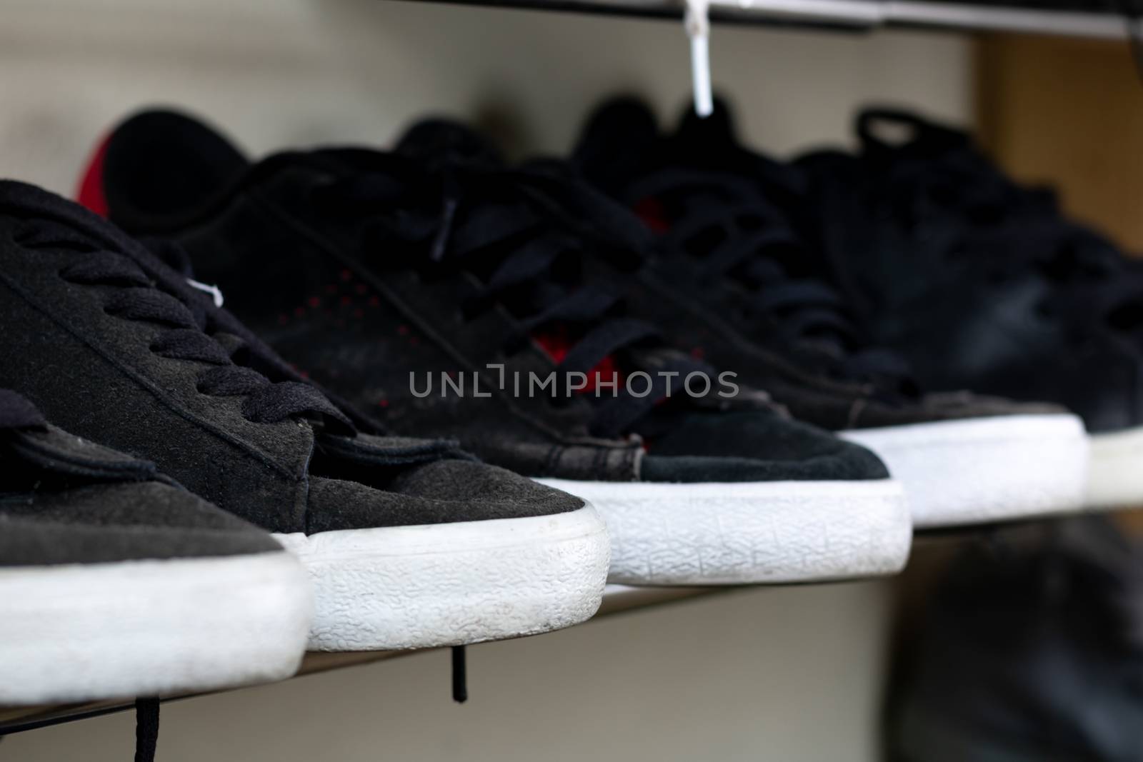 Old pairs of black sneakers on a shoe rack