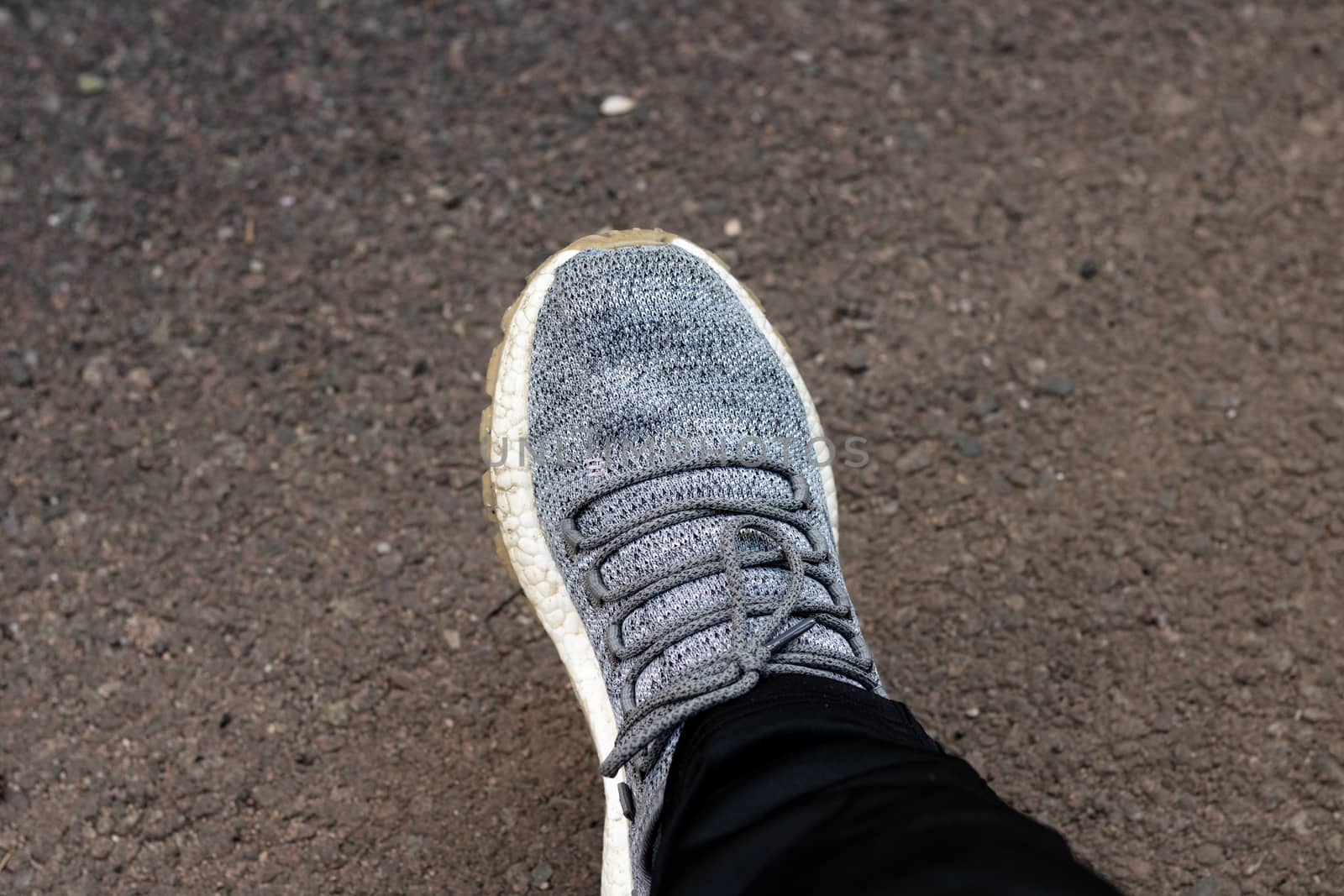 Man wearing grey sneaker and black tracksuit on tarmac