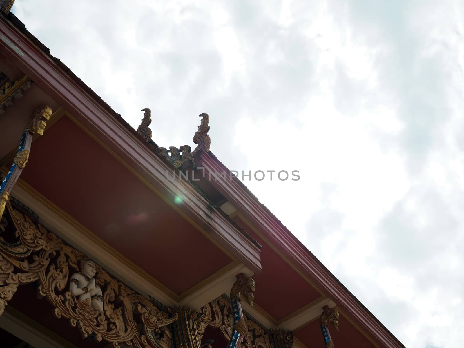 Under the roof of a Thai temple church On the background is the sky.