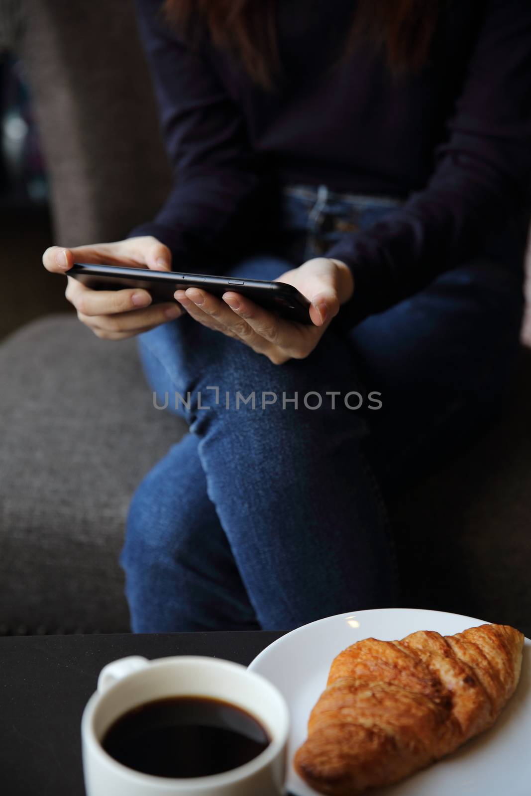 Asian female typing text message with coffe and Croissant