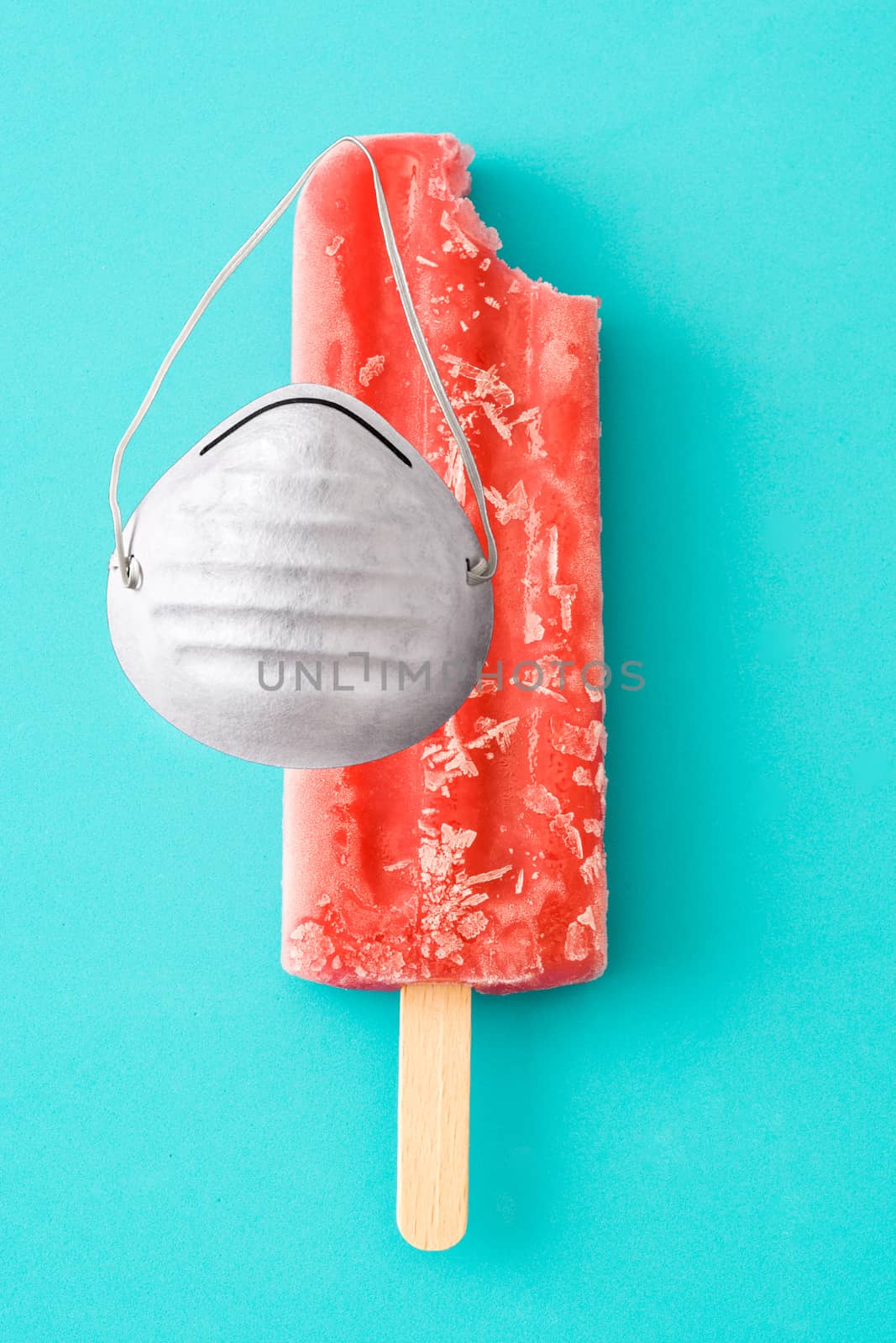 Strawberry popsicles with protective face mask on blue background