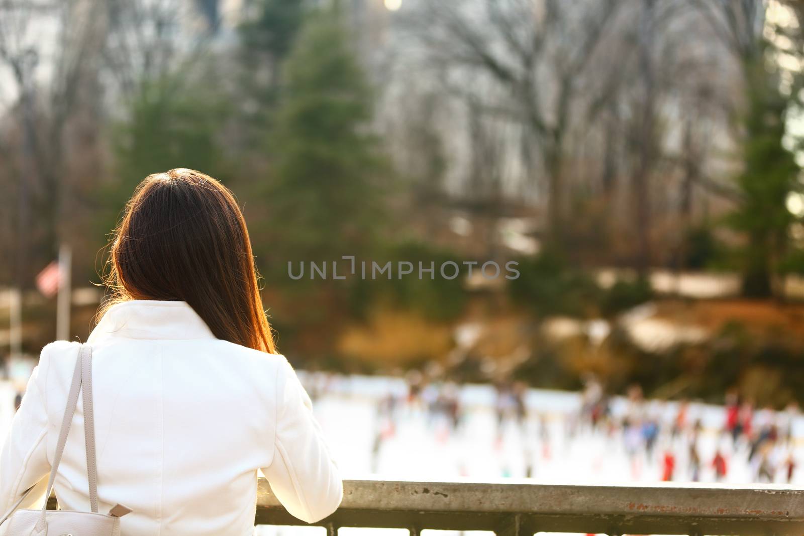 Central park skating rink - woman in New York City in late fall early winter with skating rink in background. Candid smiling multi-ethnic girl on Manhattan, USA.