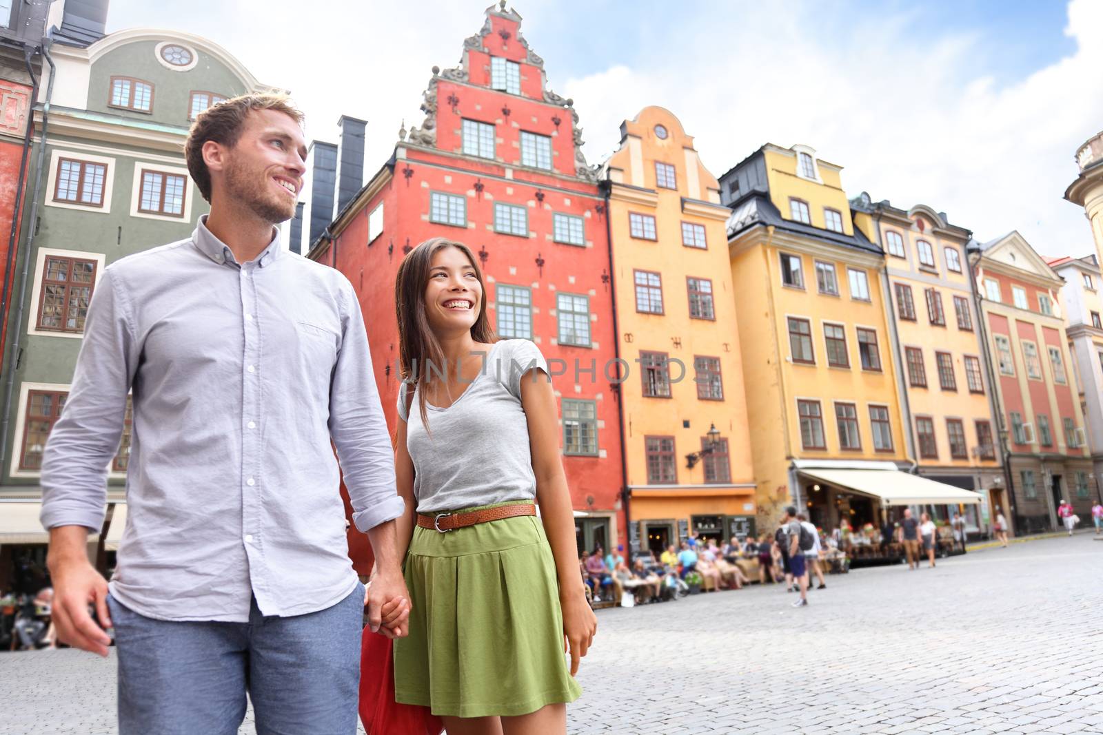 Couple in Stockholm, Sweden, Europe. Happy multiracial young couple walking outside on Stortorget big square in Gamla Stan, the old town of Stockholm. Scandinavian man, Asian woman.