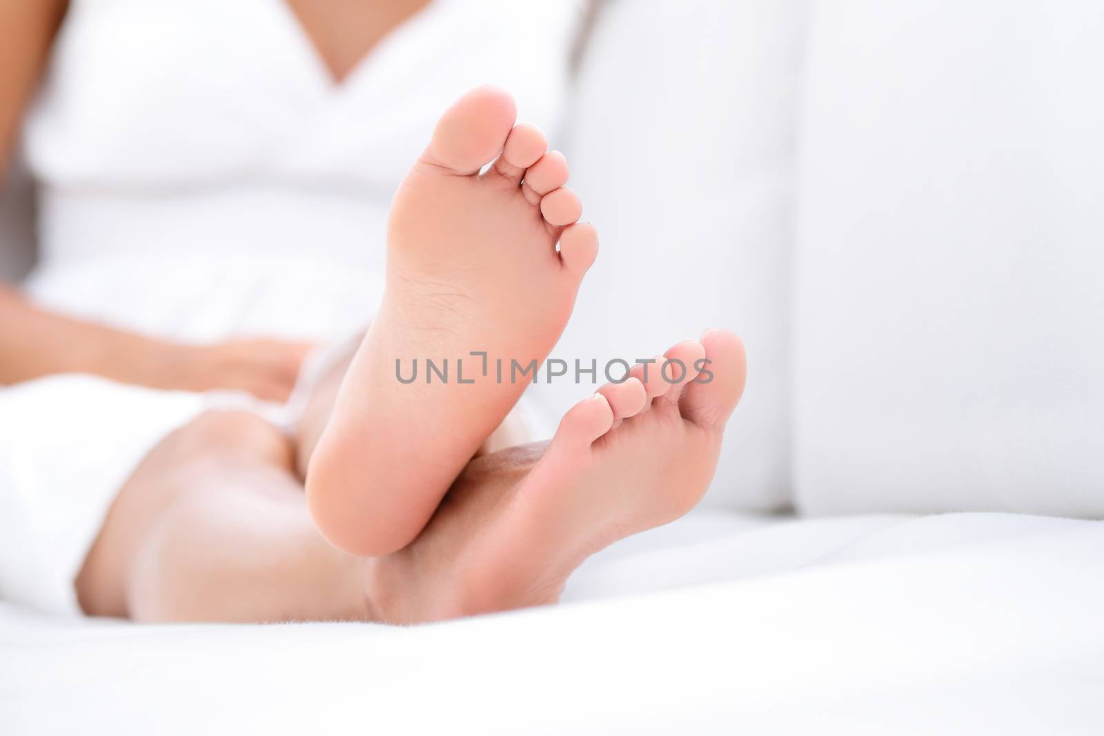 Woman feet closeup - barefoot woman relaxing in sofa. Close up of female feet of young beautiful woman sitting in couch outside.