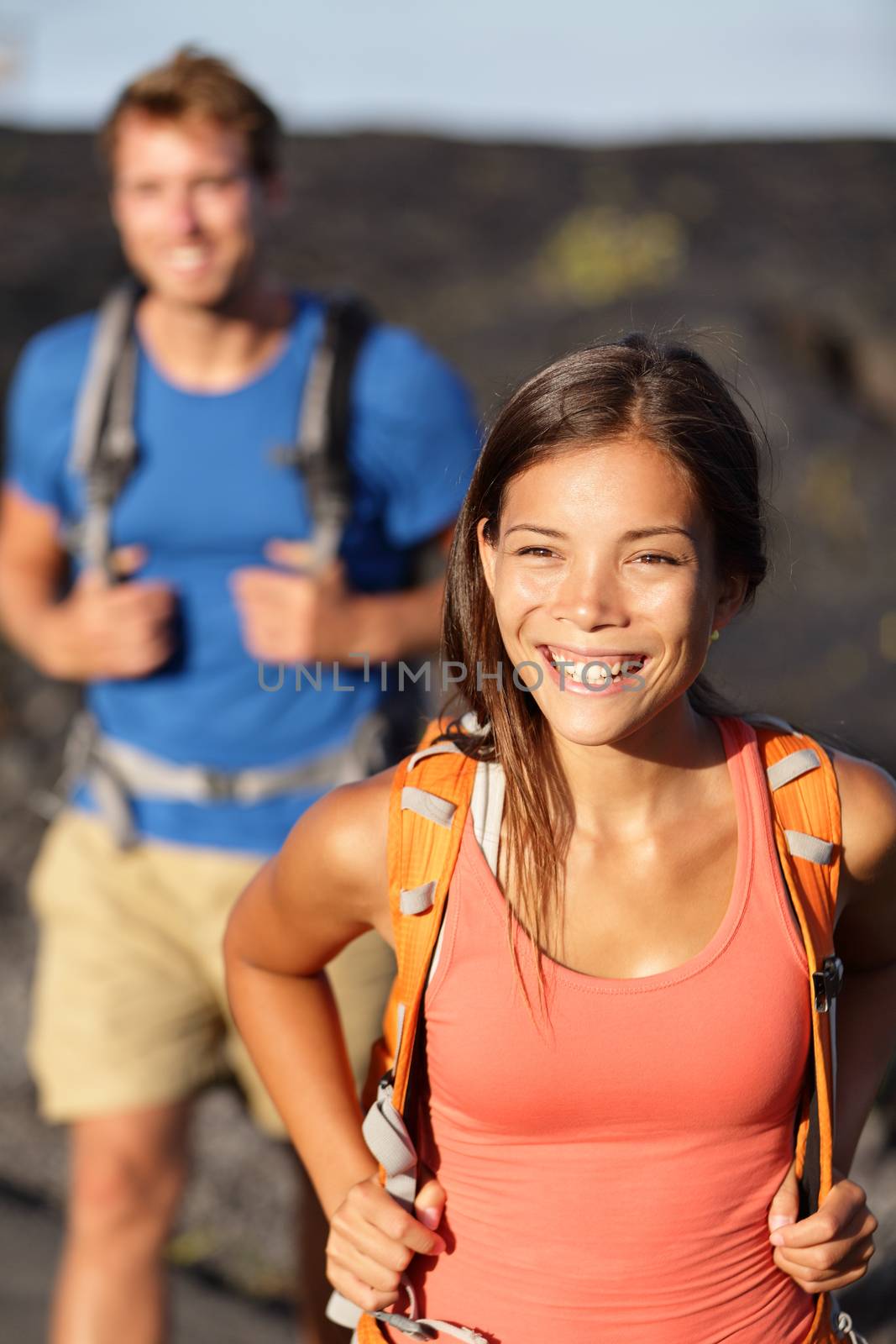 Hiking couple - Asian woman hiker walking on lava field on Hawaii. Tourists hikers on hike near Kilauea volcano around Hawaii volcanoes national park, USA.