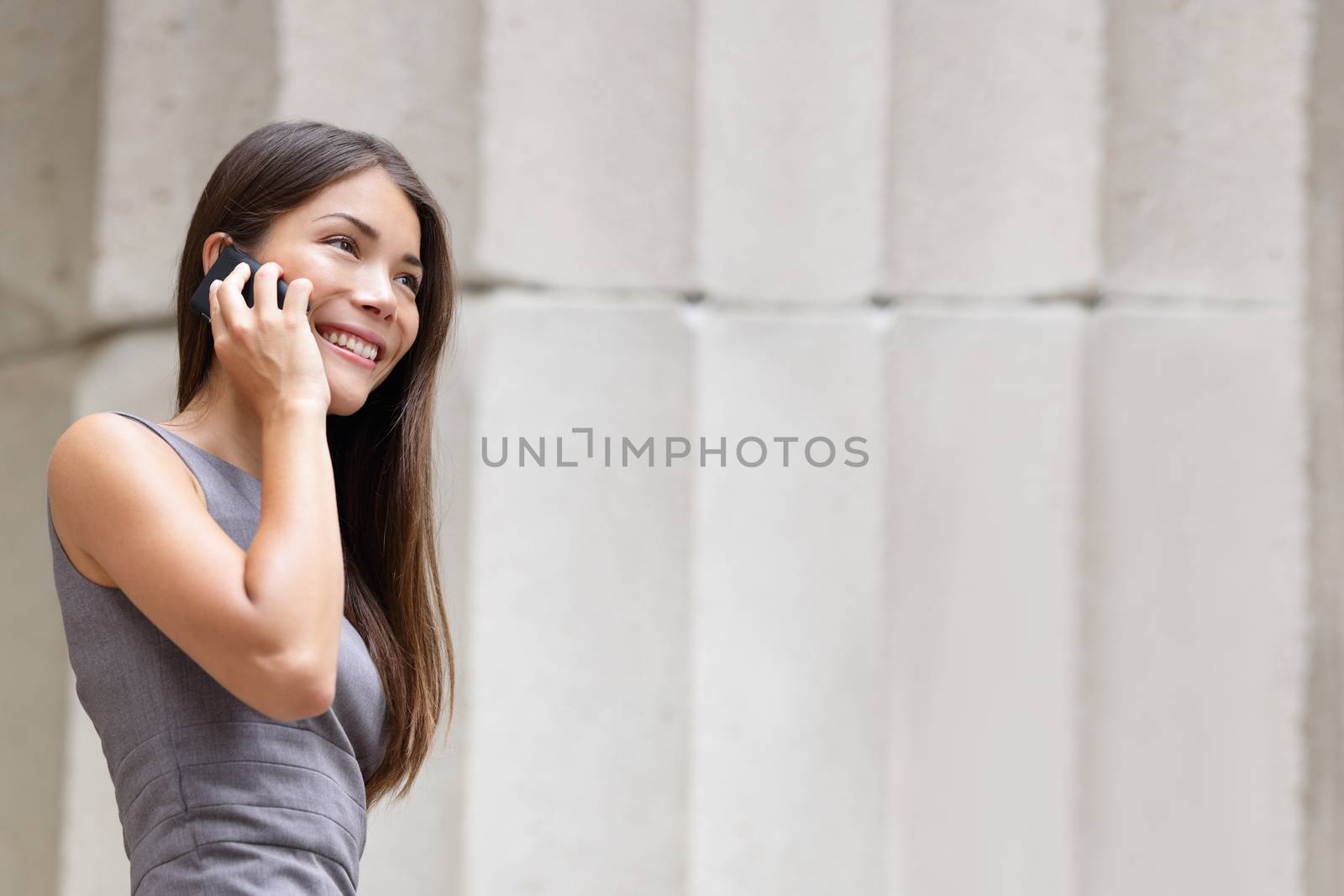 Business woman lawyer talking on smartphone outside. Successful young multiracial Caucasian / Asian Chinese professional woman.