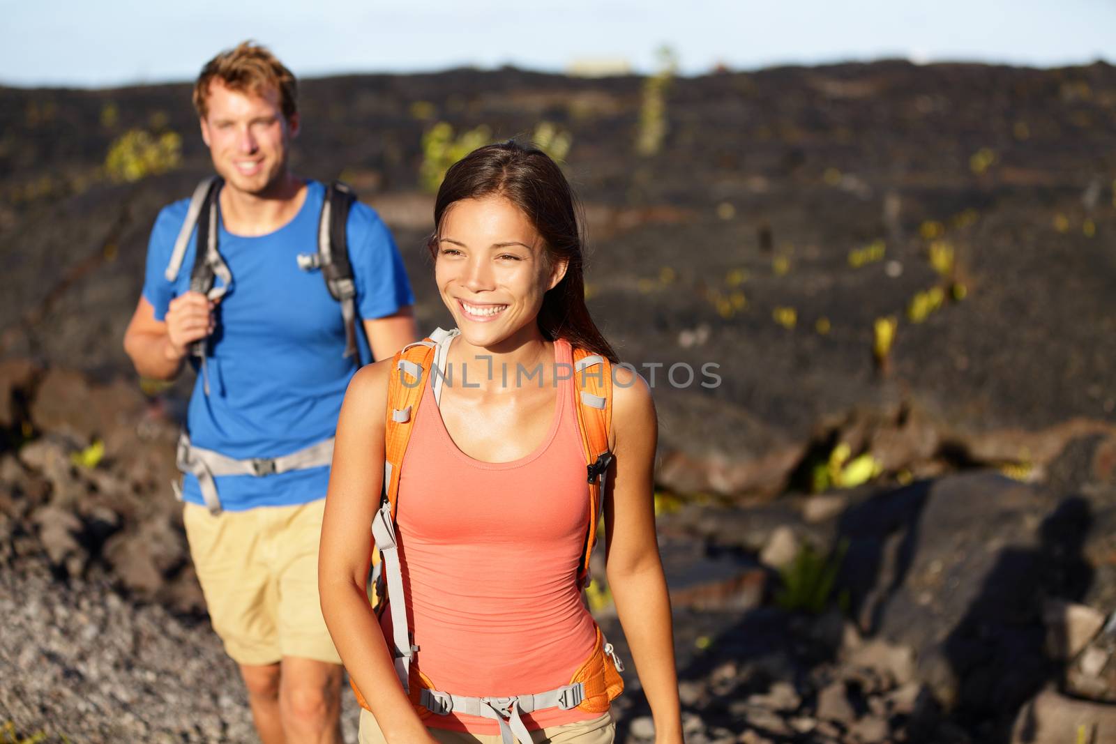 Hiking people - couple walking on lava field on Hawaii. Tourists hikers on hike near Kilauea volcano around Hawaii volcanoes national park, USA.