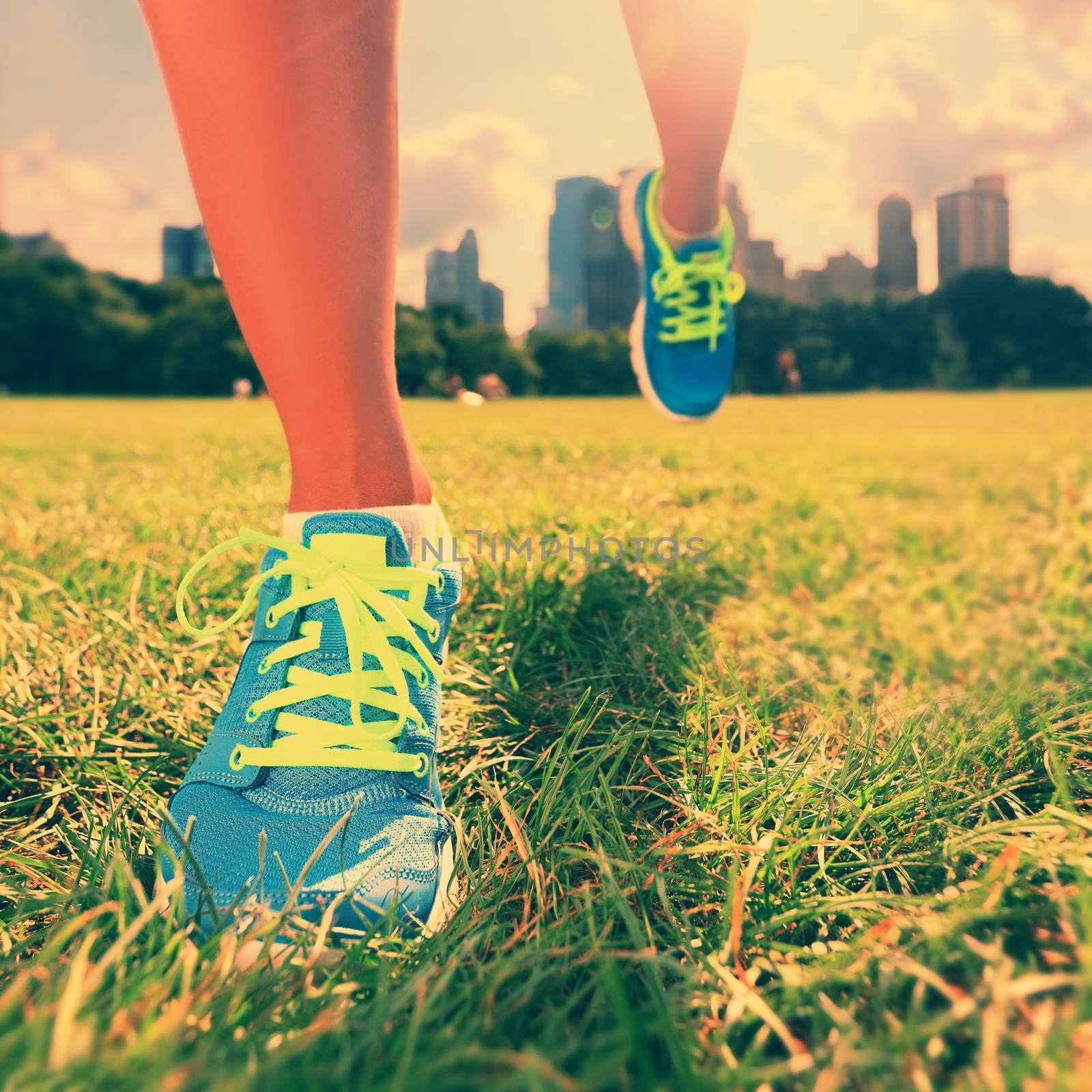 Healthy lifestyle runner - running shoes on woman athlete running shoes on grass. Female jogger womens shoes in Central Park, New York City.