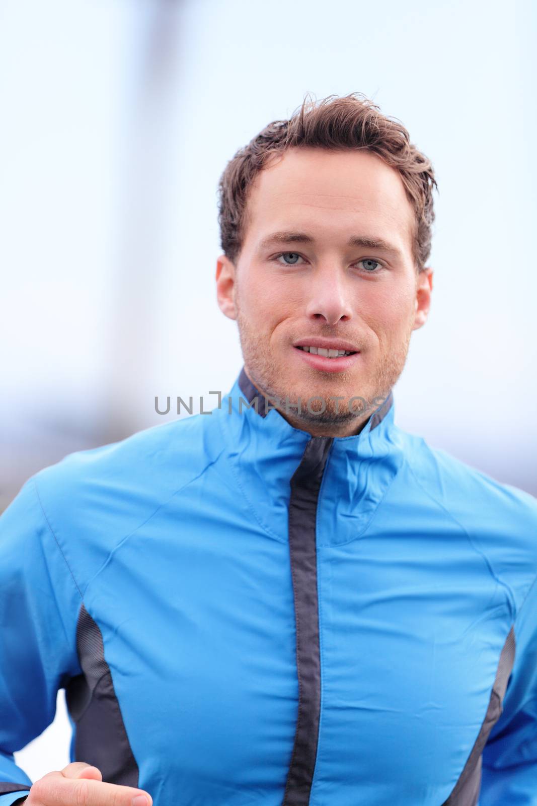 Man running outdoors closeup in fall in runner outfit jacket. Male athlete jogging outside in autumn training on cold day. Healthy lifestyle concept.