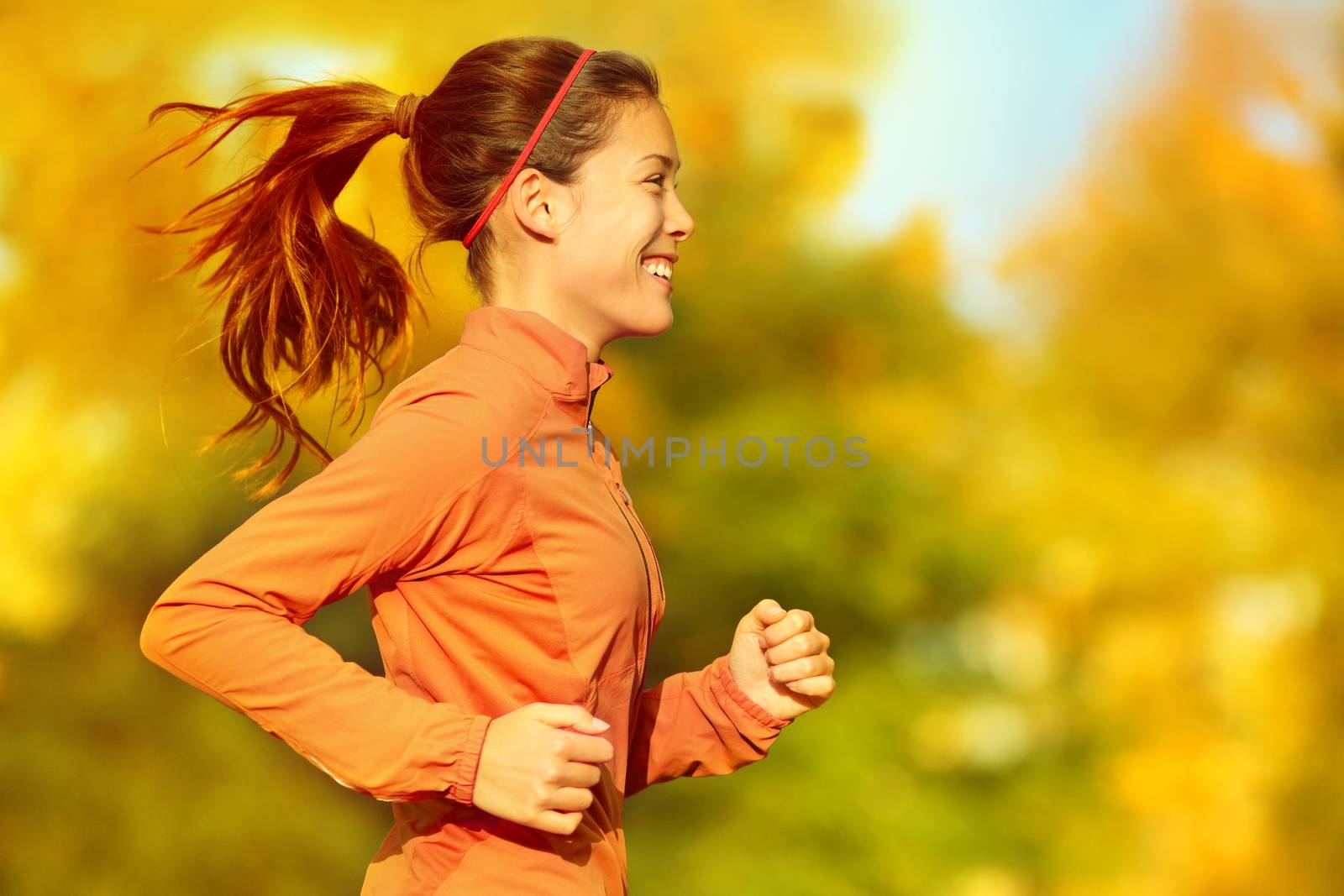 Woman runner running in fall autumn forest. Female fitness girl jogging on path in amazing fall foliage landscape nature outside.