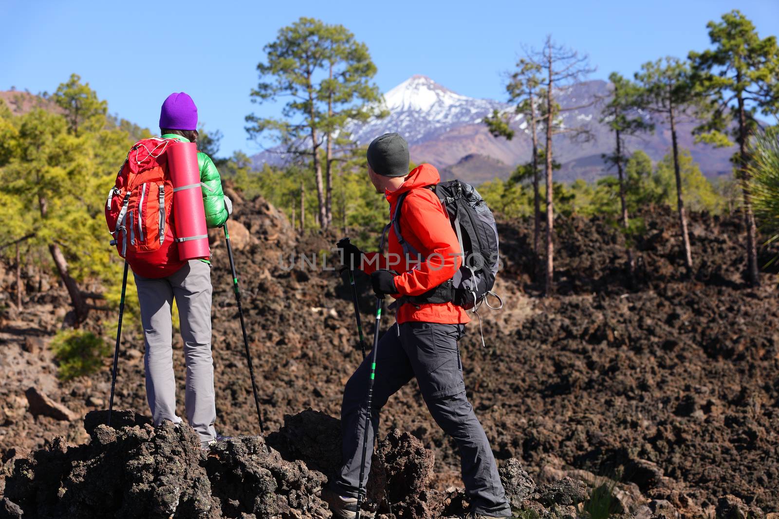 People hiking - healthy active lifestyle hikers. Hiker couple hiking in beautiful mountain nature landscape. Woman and man hikers walking during hike on volcano Teide, Tenerife, Canary Islands, Spain.