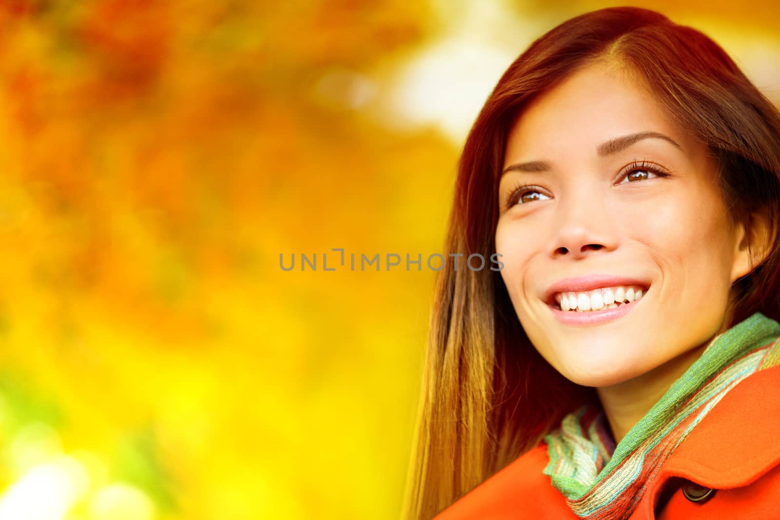 Autumn / Fall woman in colorful foliage in city park forest smiling happy. Portrait of modern girl and colorful leaves outdoor in fall forest foliage. Mixed race Asian Caucasian female model.