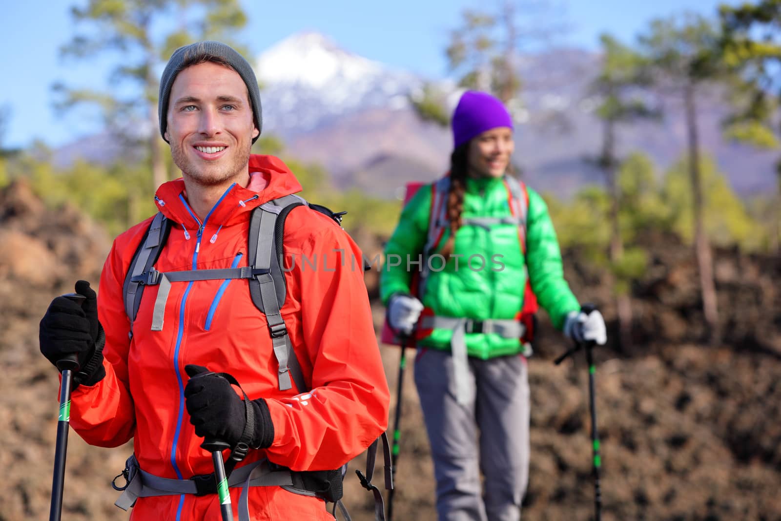 Hiking hikers couple - healthy active lifestyle. Hiker couple hiking in beautiful mountain nature landscape. Woman and man hikers walking during hike on volcano Teide, Tenerife, Canary Islands, Spain.