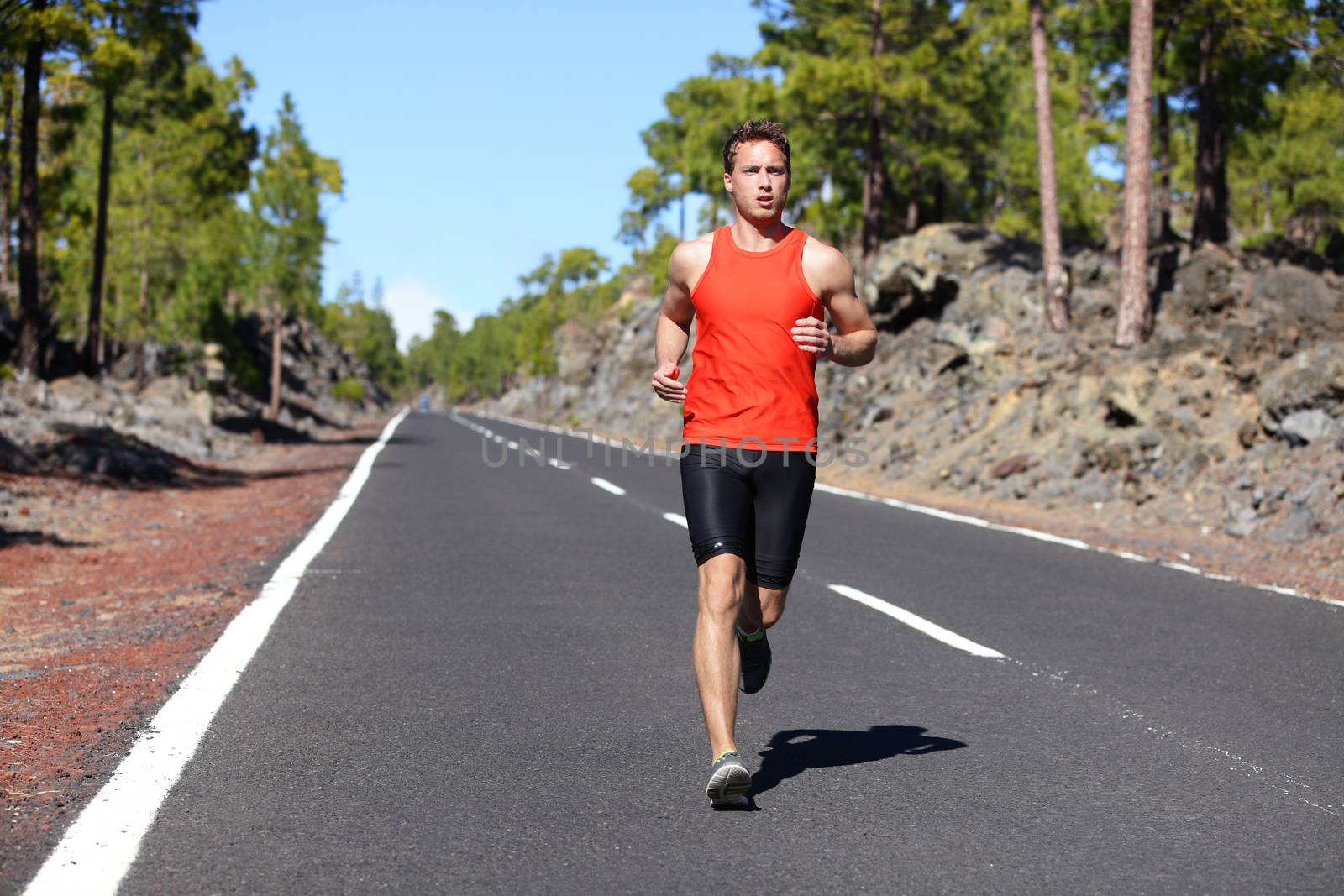 Running man - male runner jogging outdoors on road training for marathon run as part of healthy lifestyle. Close up of fit fitness model during outdoor workout in summer. Caucasian guy.
