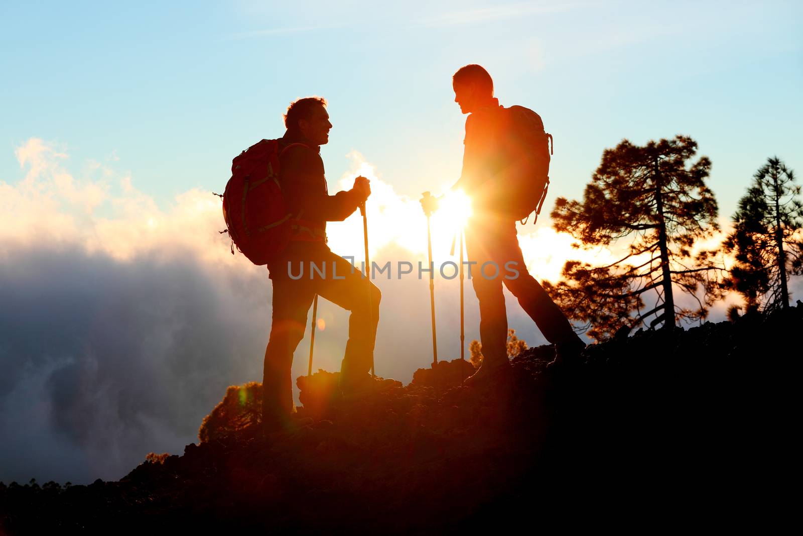 Hiking couple looking enjoying sunset view on hike by Maridav
