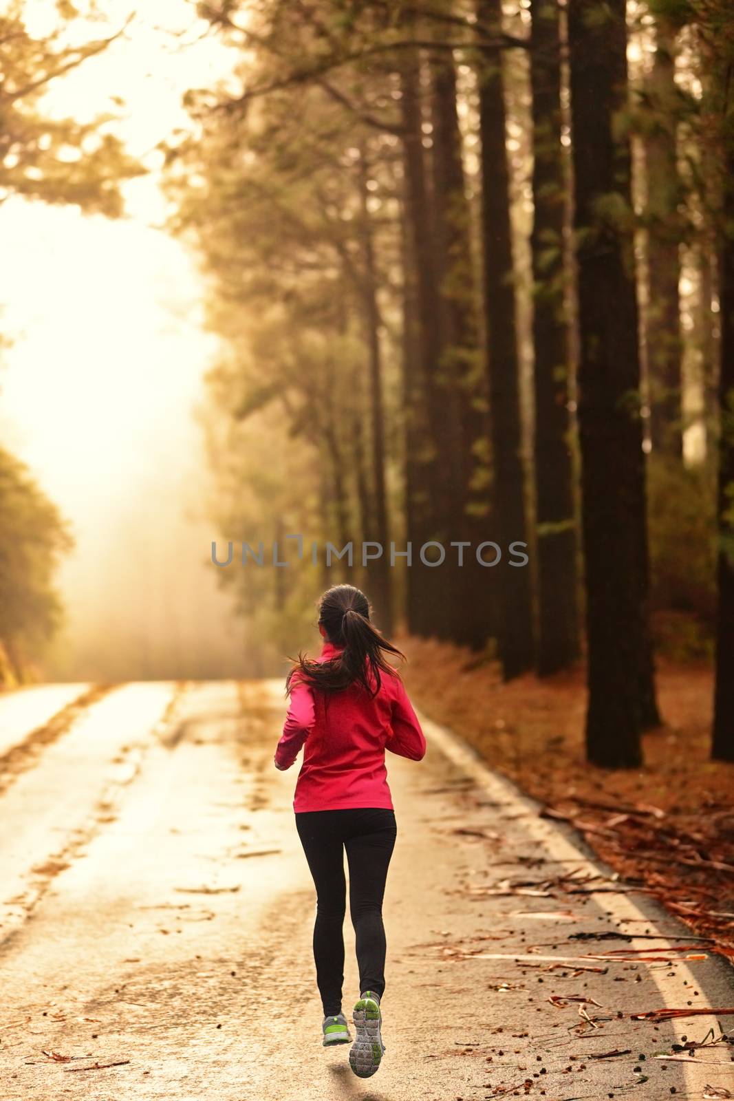 Athlete running on road in morning sunrise by Maridav