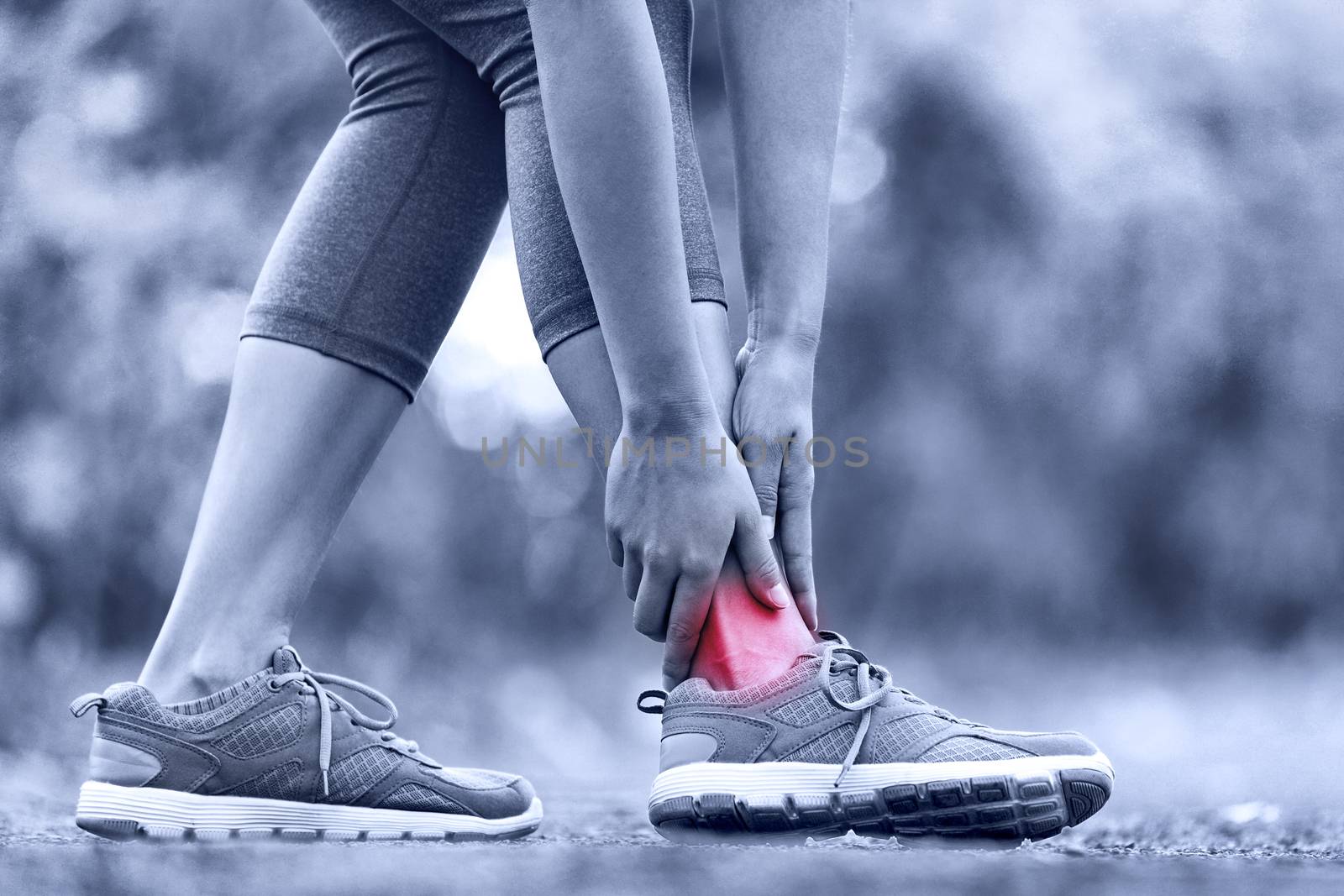 Broken twisted ankle - running sport injury. Female runner touching foot in pain due to sprained ankle.