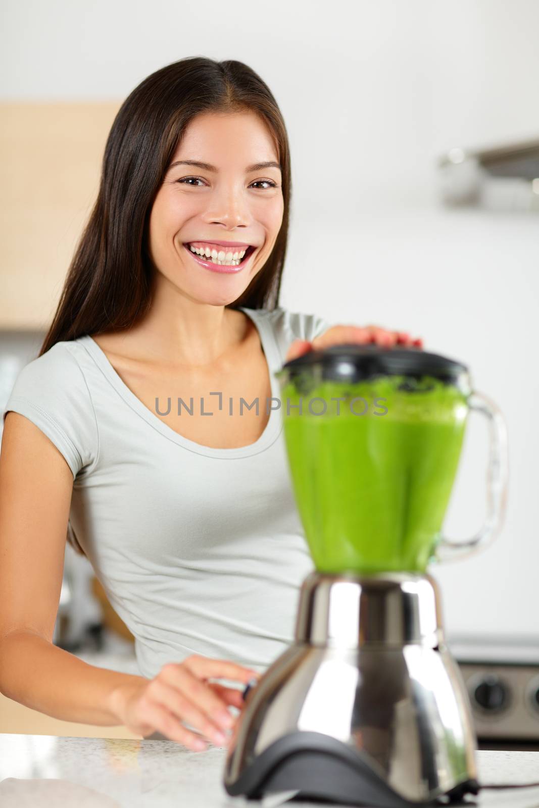 Smoothie woman making vegetable green smoothies with blender home in kitchen. Healthy eating lifestyle concept portrait of beautiful young woman preparing drink with spinach, carrots, celery etc.