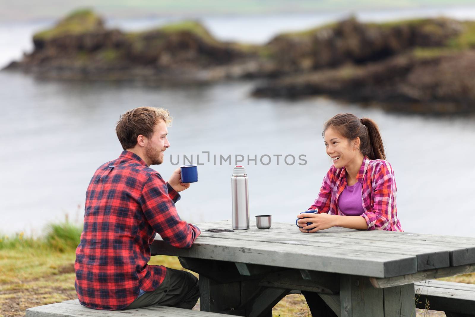 Camping couple sitting at table drinking coffee by Maridav