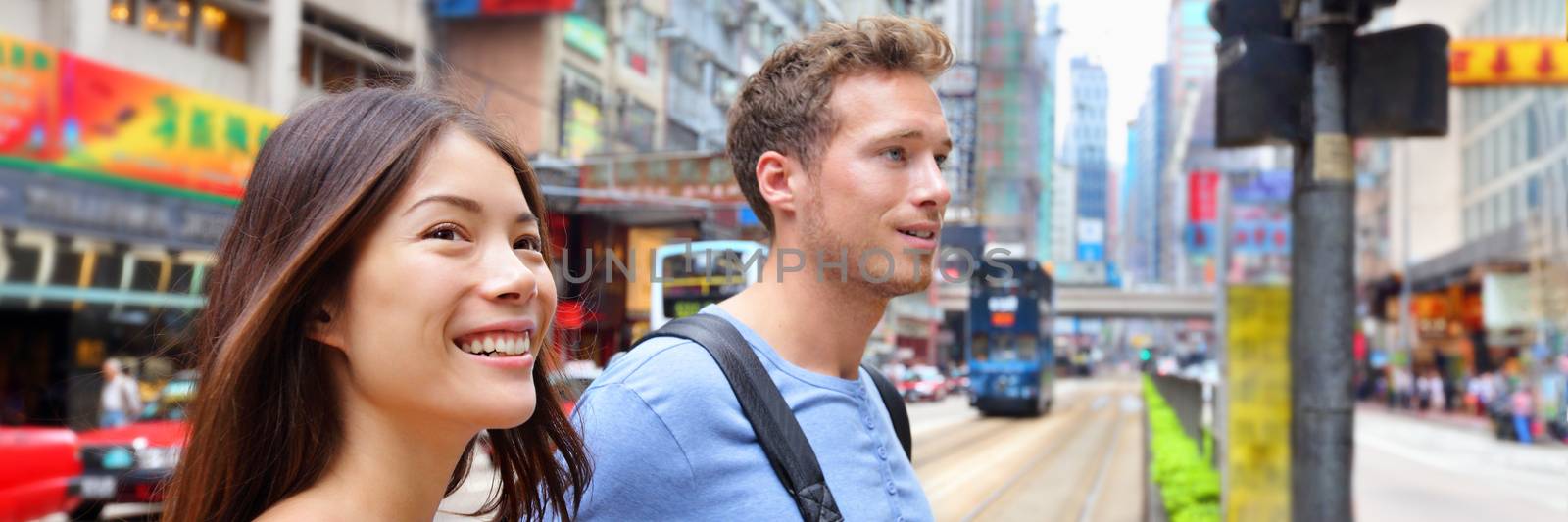 Couple walking in Hong Kong city street young people lifestyle banner panorama. Asian woman and Caucasian man tourists enjoying Asian summer travel holiday in China.