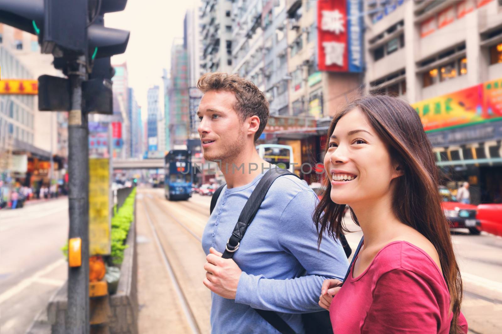 Young people crossing the street in downtown Hong Kong China Travel lifestyle. Caucasian Asian multiracial couple tourists walking traveling discovering the world during their gap year. by Maridav