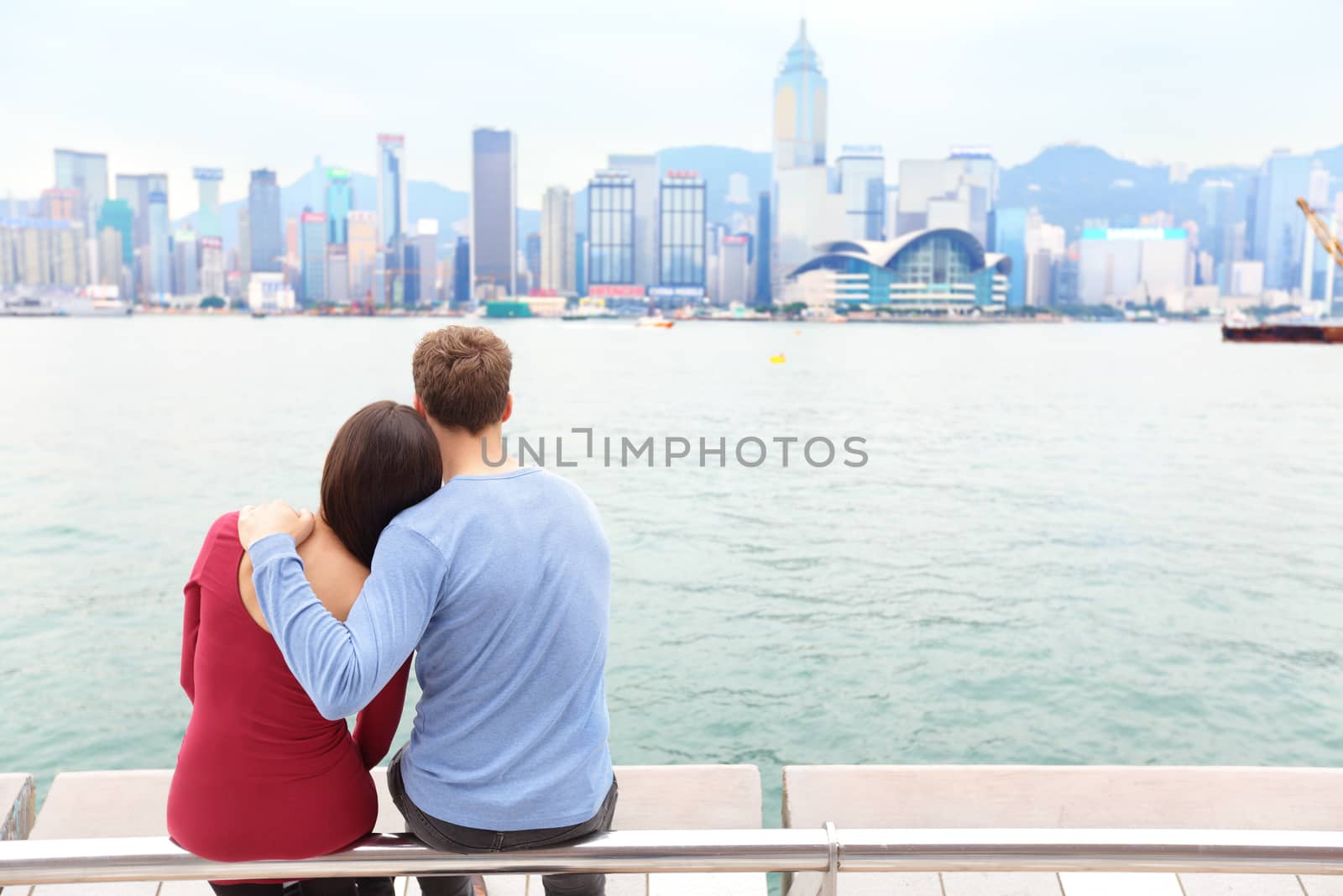 Hong Kong skyline and Victoria harbour. Couple tourists enjoying view and sightseeing on Tsim Sha Tsui Promenade and Avenue of Stars in Victoria harbour, Kowloon, Hong Kong. Tourism travel concept.