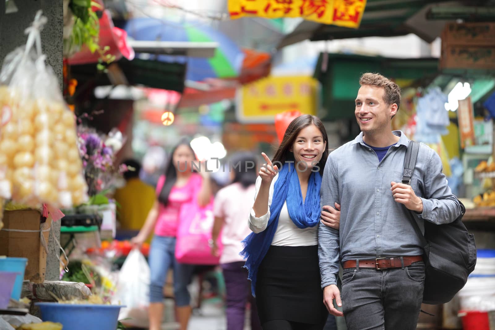 Tourists shopping in street market in Hong Kong. Couple walking looking around at small shops. Asian woman, Caucasian man.