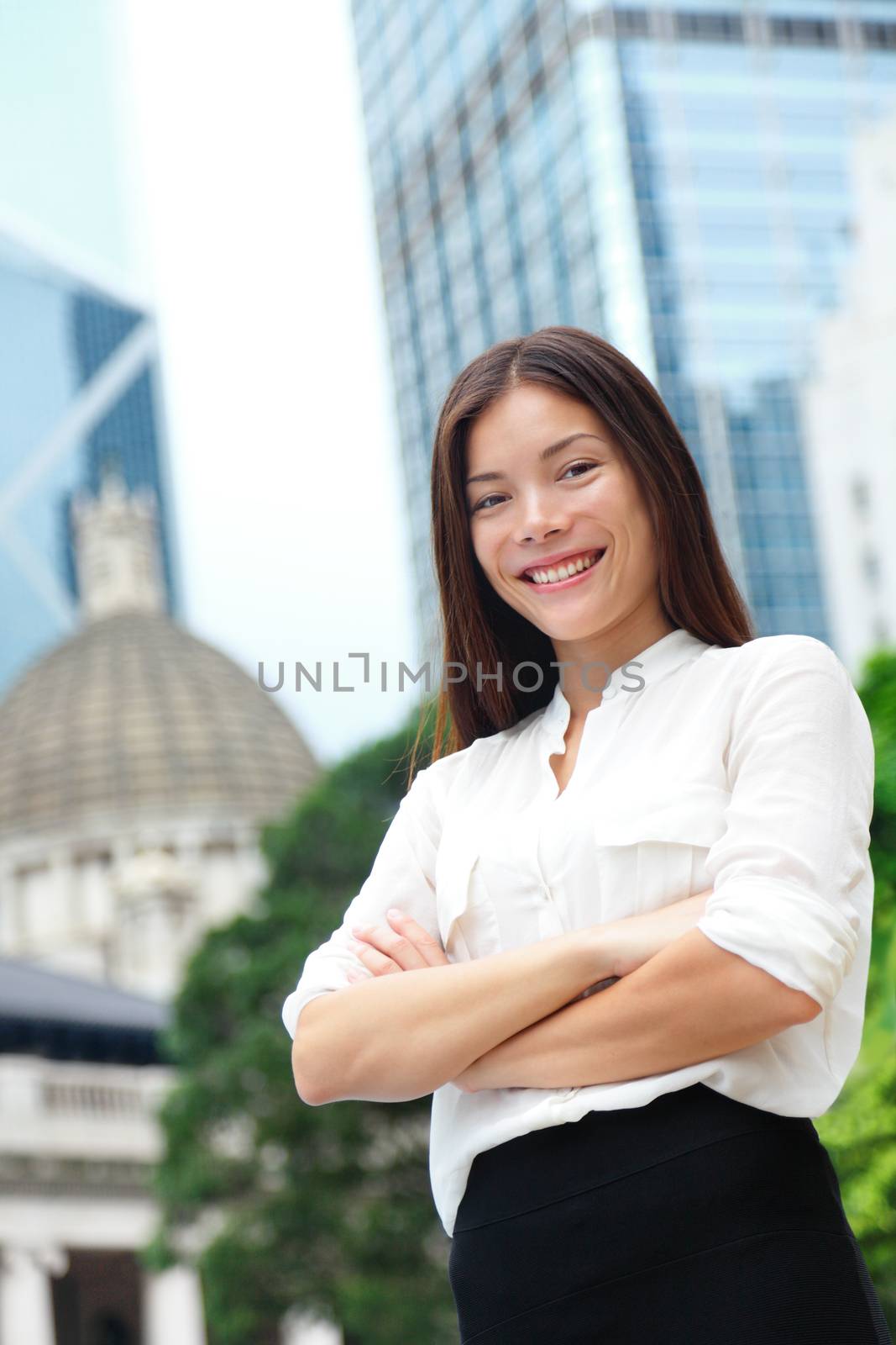 Business woman smiling portrait in Hong Kong. Businesswoman standing happy and successful in suit cross-armed. Young multiracial Chinese Asian / Caucasian female professional in central Hong Kong.