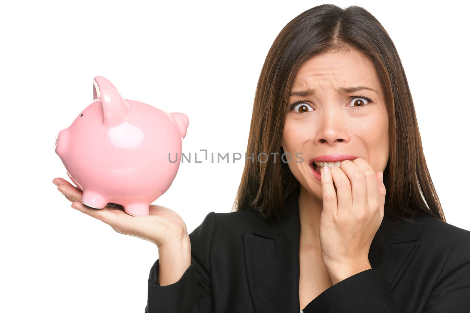 Money stress - business woman holding piggy bank. Debt, bankruptcy and savings concepts with stressed female businesswoman biting nails nervous isolated